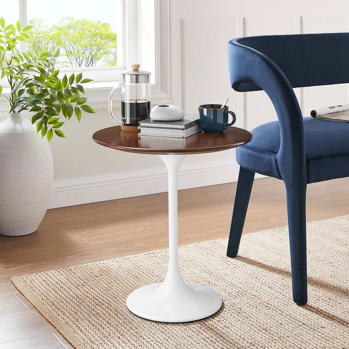 Round walnut and white pedestal side table styled beside a blue accent chair in a cozy room || EEI-5679-WHI-WAL || front_room