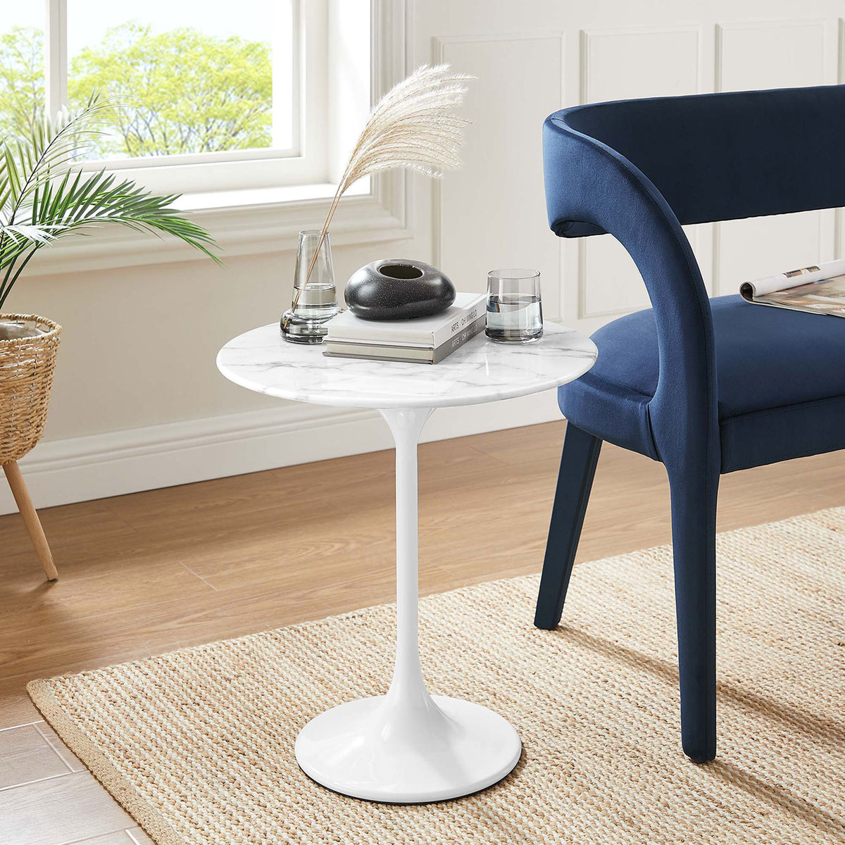 White faux marble pedestal side table beside a blue chair on a natural woven rug || EEI-5680-WHI-WHI || front_angle_room