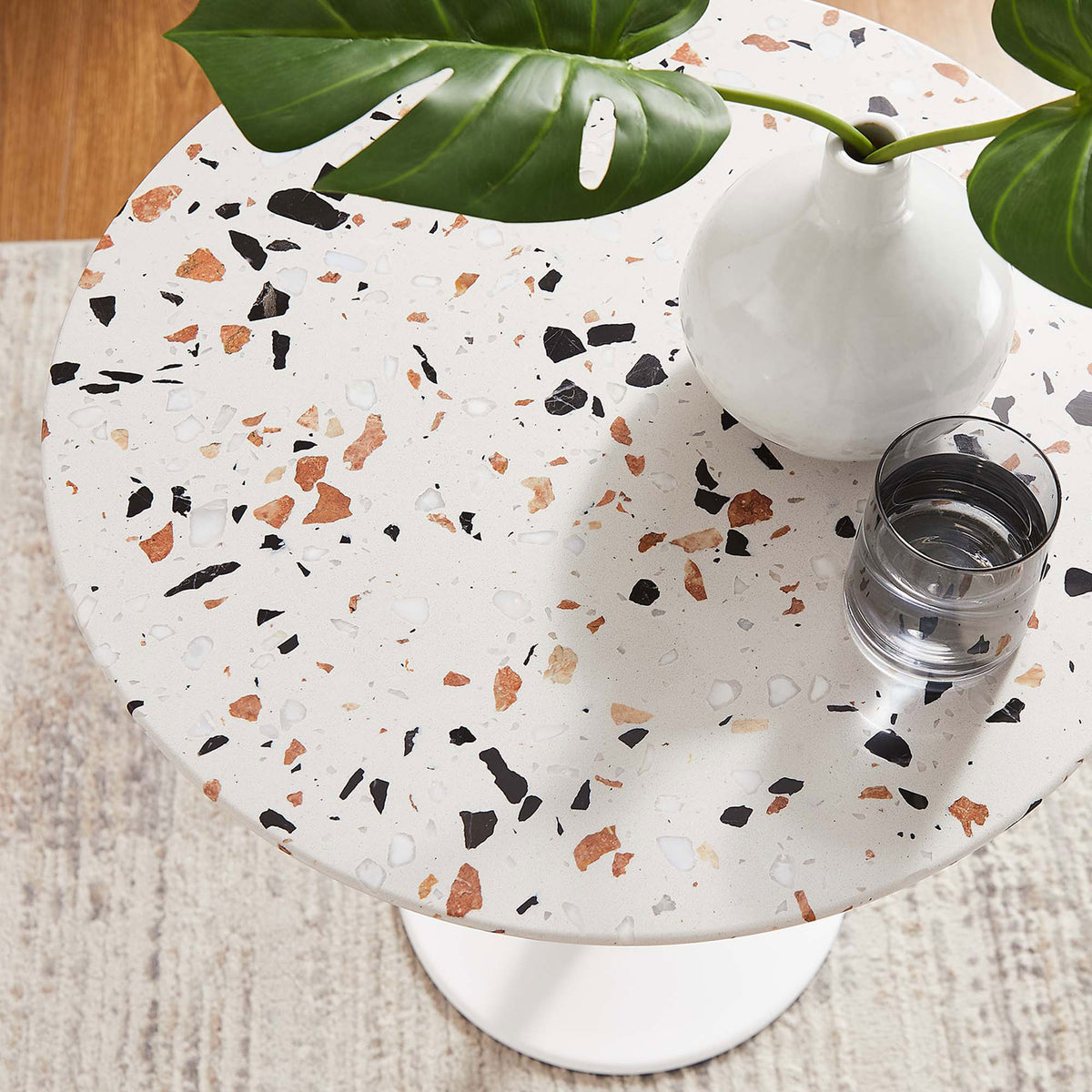 Styled terrazzo tabletop with vase, greenery, and glass accenting the speckled surface in a cozy room || EEI-5682-WHI-TER || detail_room