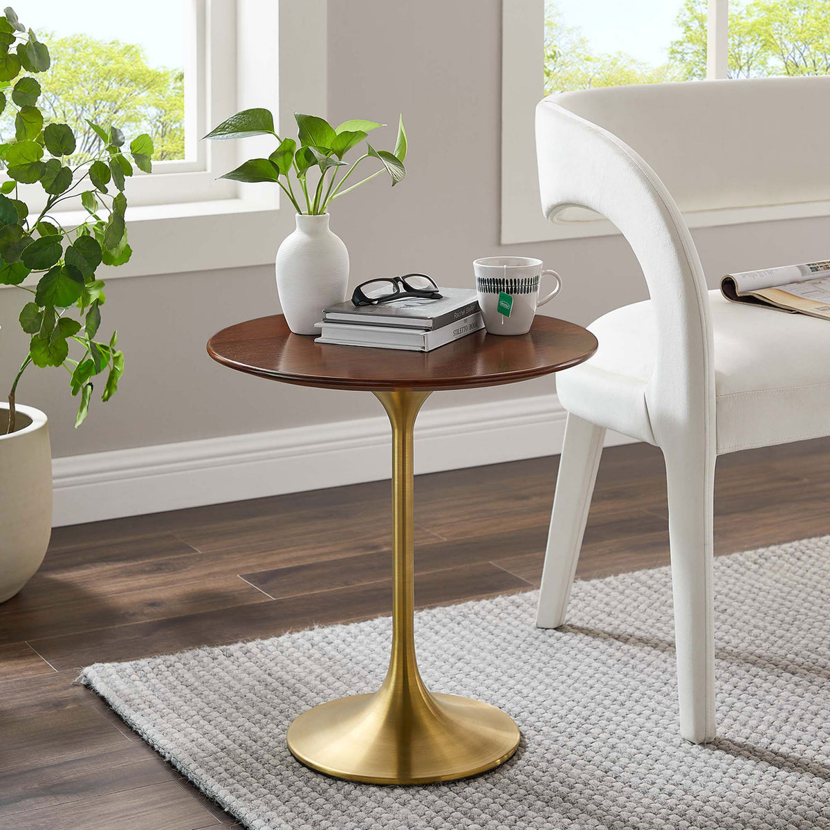 Walnut and gold round side table styled beside a white chair in a bright modern living room || EEI-5684-GLD-WAL || front_angle_room
