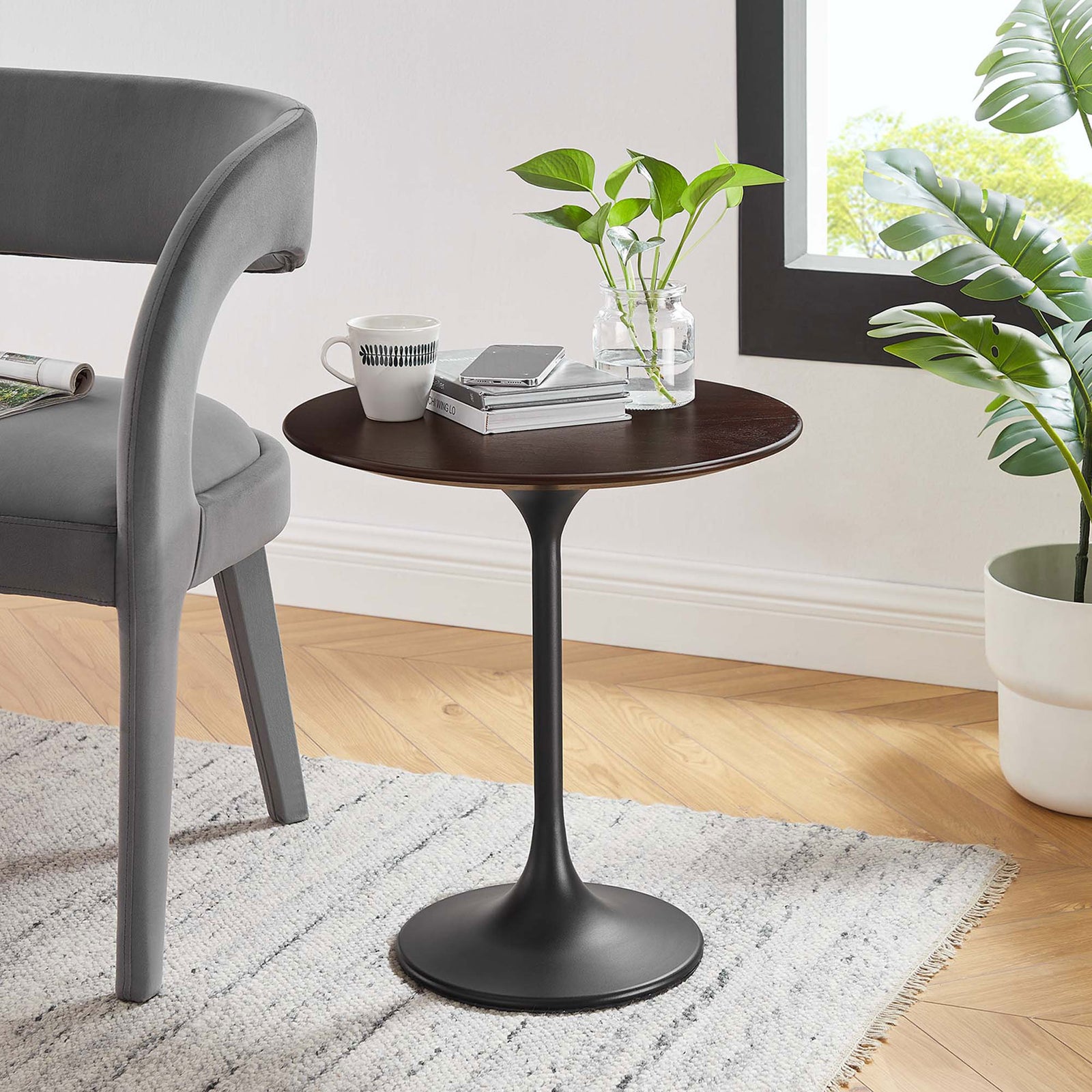Modern black cherry pedestal side table beside chair styled with books and plants || EEI-5689-BLK-CHE || front_angle_room