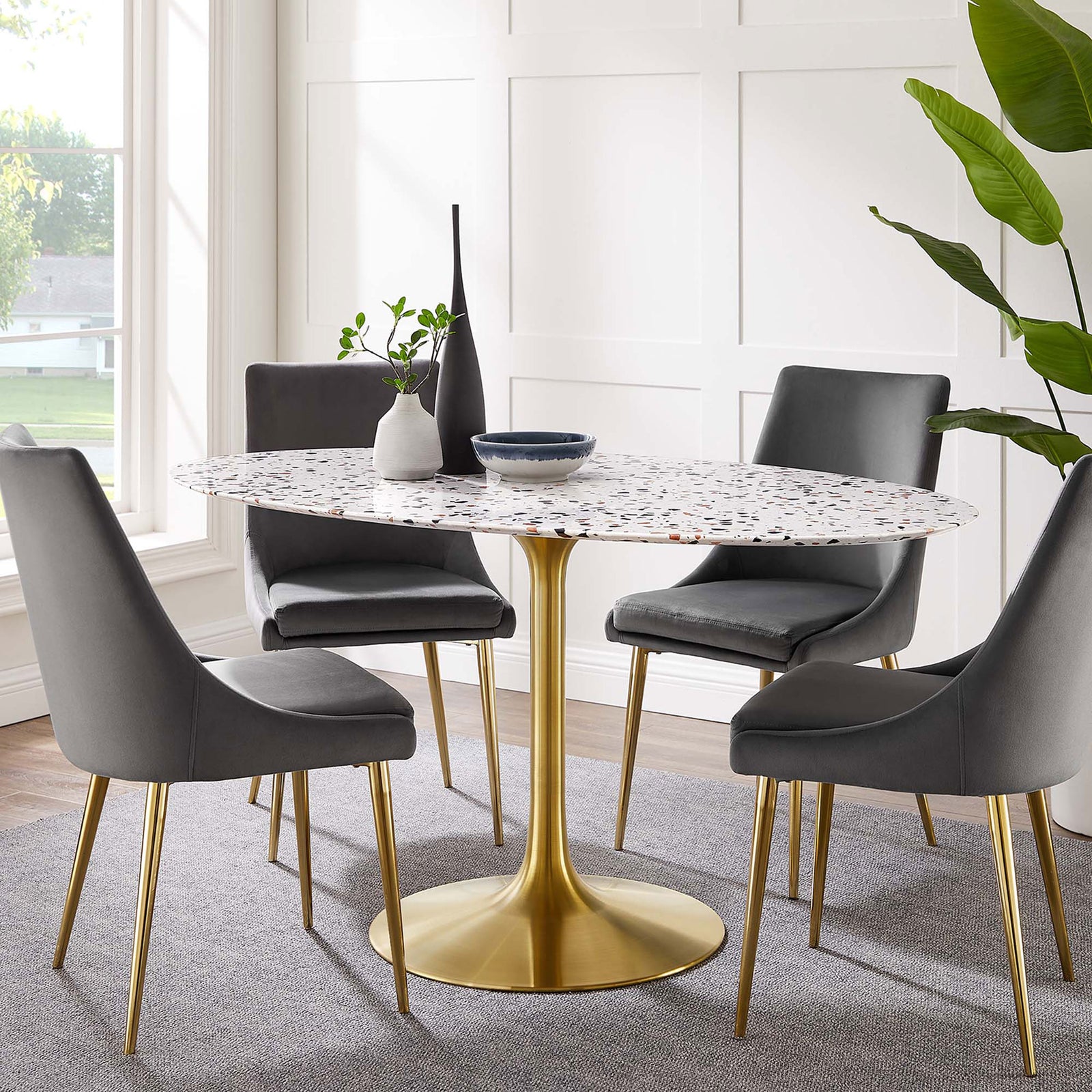 Terrazzo dining table with brushed gold pedestal base styled with chairs for a bright modern dining area || EEI-5736-GLD-WHI || front_angle_room