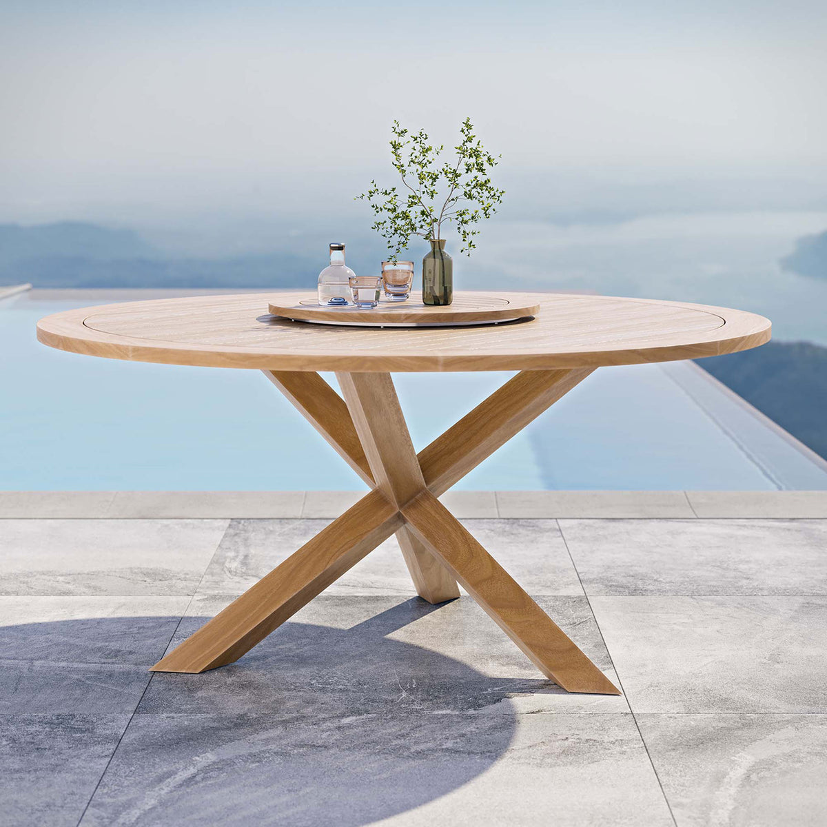 Round teak dining table with lazy Susan styled outdoors beside a modern pool || EEI-5745-NAT || front_angle_room