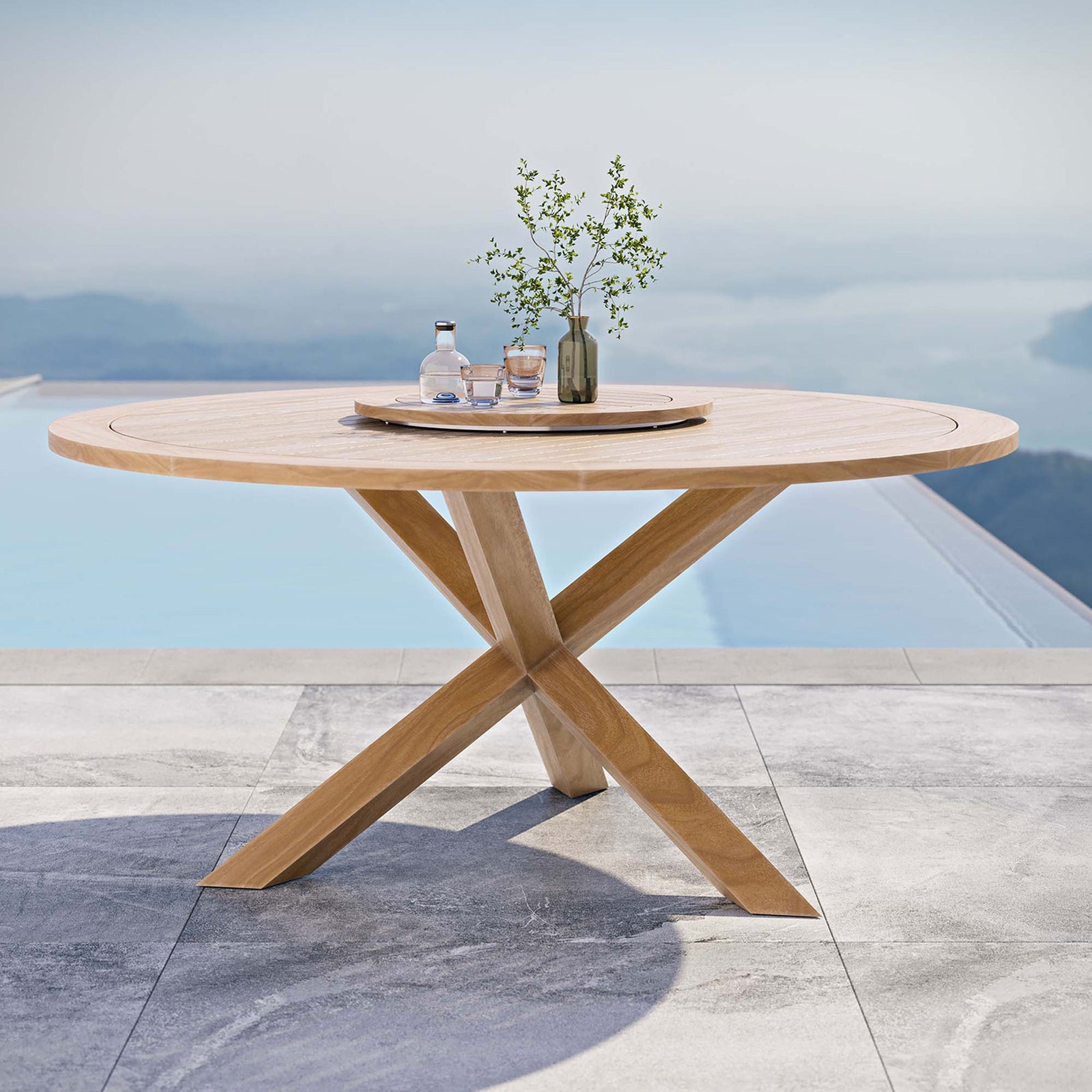Round teak dining table with lazy Susan styled outdoors beside a modern pool || EEI-5745-NAT || front_angle_room