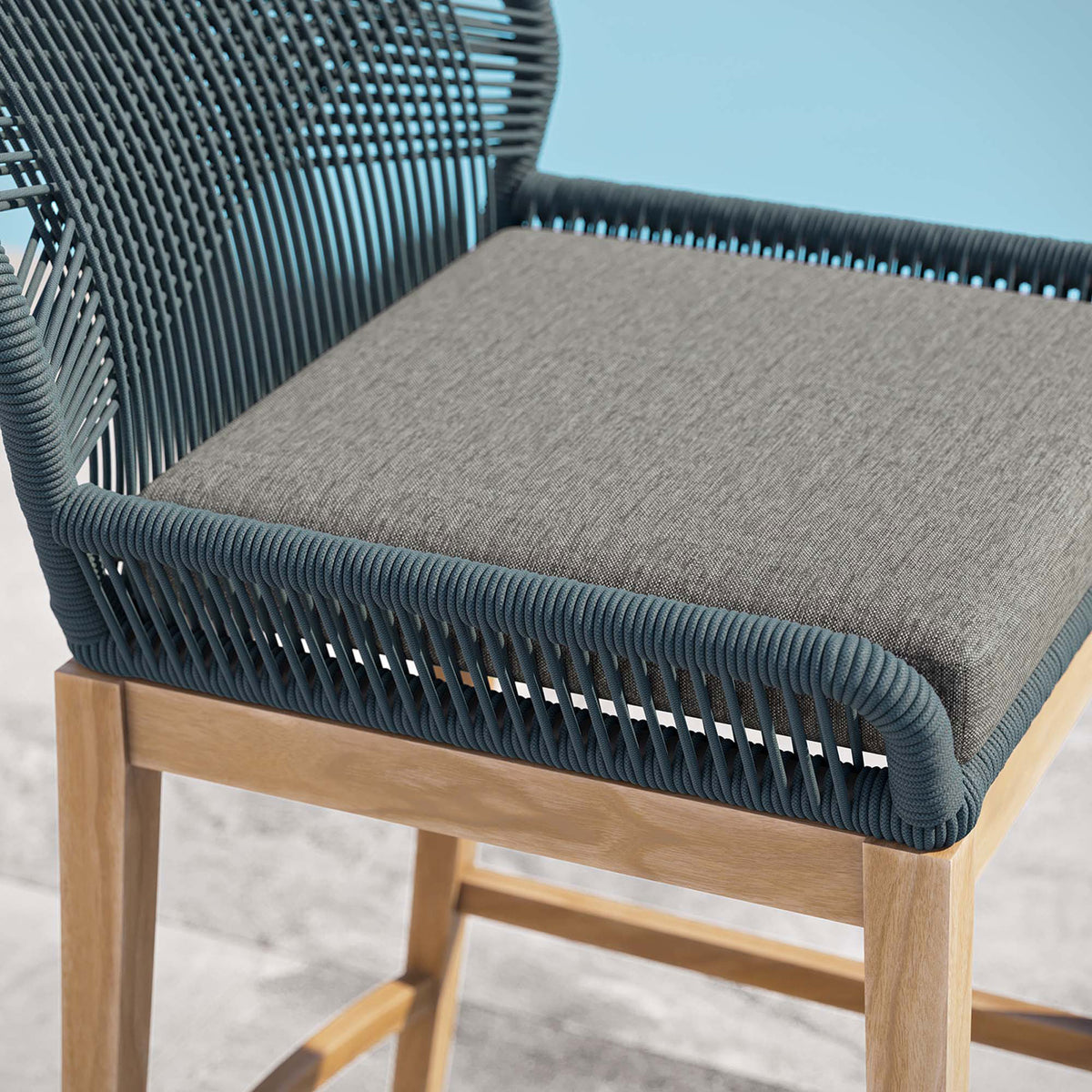 Gray seat cushion and tightly wrapped blue rope frame on the Wellspring bar stool beside a serene pool. || EEI-5746-BLU-GPH || detail_room