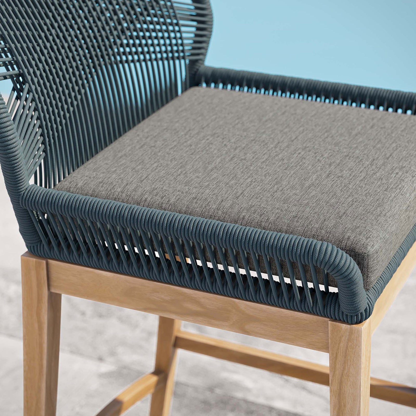 Gray seat cushion and tightly wrapped blue rope frame on the Wellspring bar stool beside a serene pool. || EEI-5746-BLU-GPH || detail_room