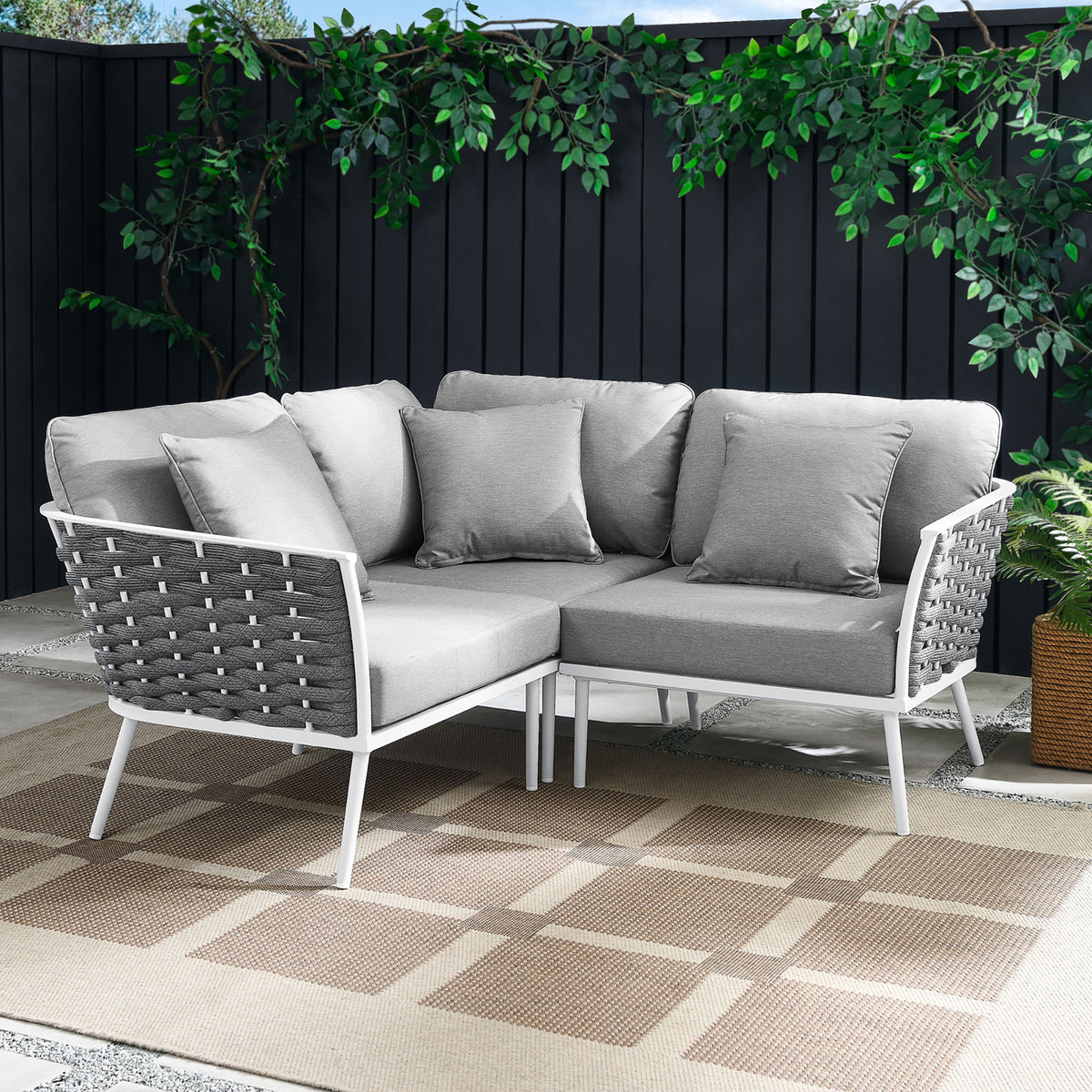 Gray rope sectional anchors a modern patio with white frame, taupe outdoor rug, and lush greenery || EEI-5752-WHI-GRY || front_angle_room