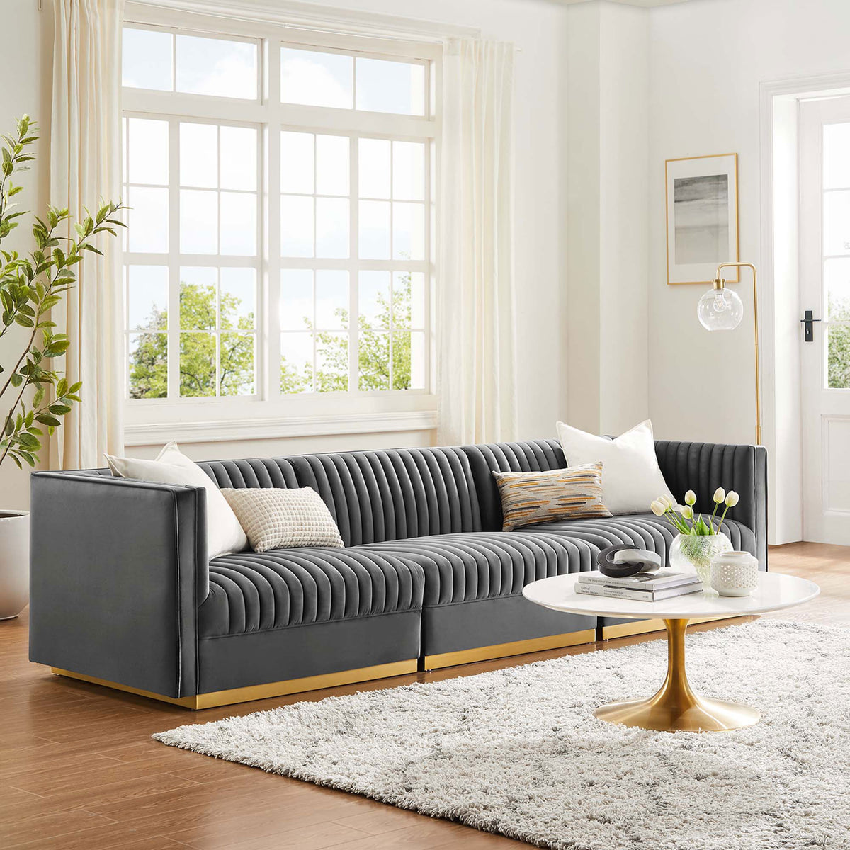 Gray channel tufted modular sofa styled in a bright living room with a round white and gold coffee table || EEI-5825-GRY || front_room