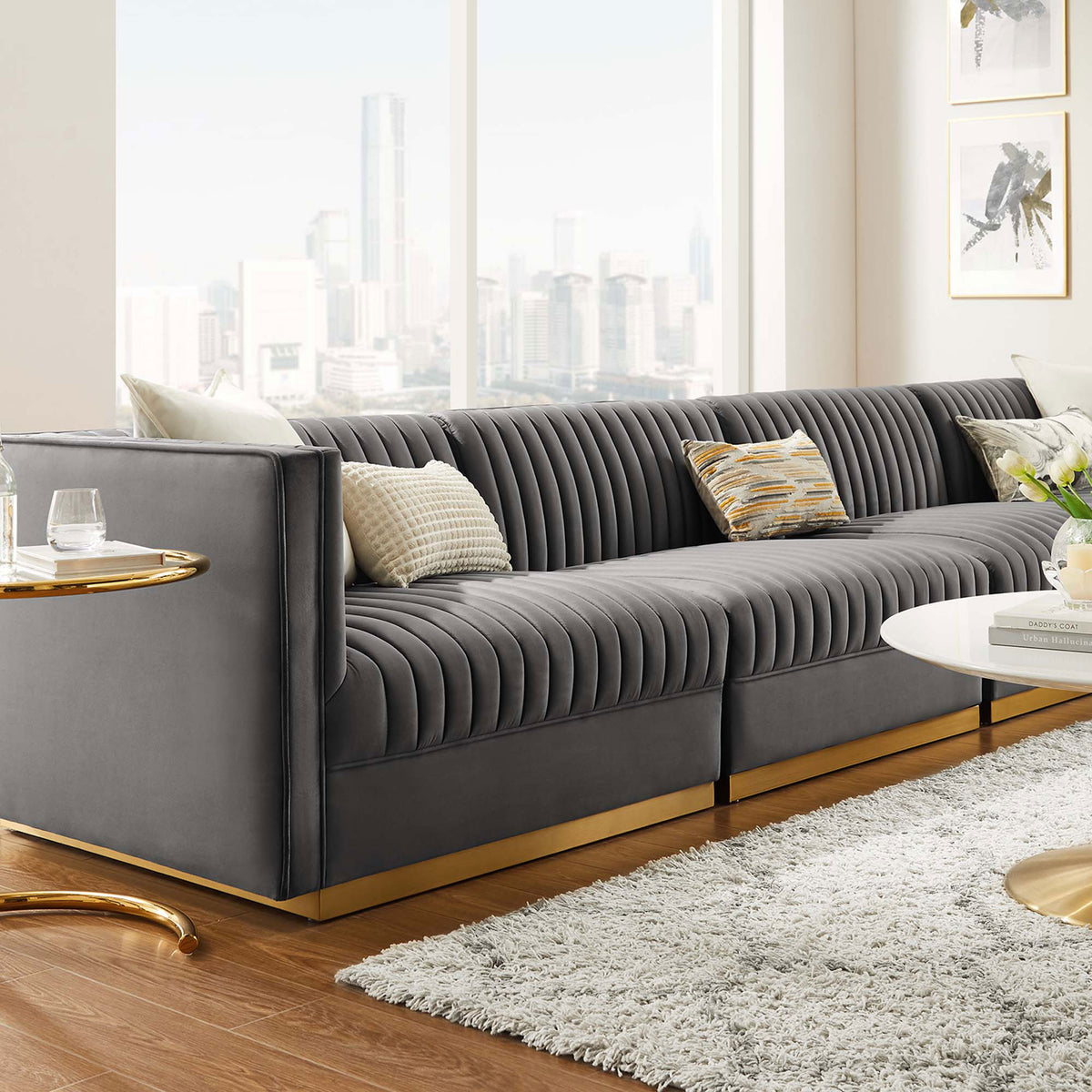 Gray channel tufted velvet sectional sofa with gold base styled in a bright modern living room with city views || EEI-5827-GRY || detail_room