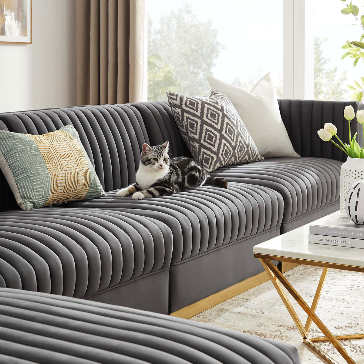 Gray velvet modular sectional styled in a bright living room with accent pillows and gold base detail. || EEI-5828-GRY || detail_room
