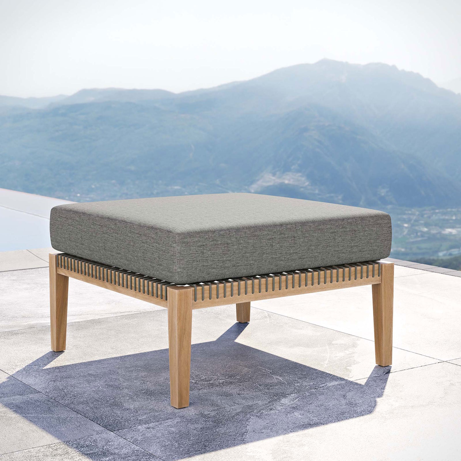 Graphite cushion teak patio ottoman overlooking a scenic view for a relaxing outdoor lounge || EEI-5854-GRY-GPH || front_angle_room