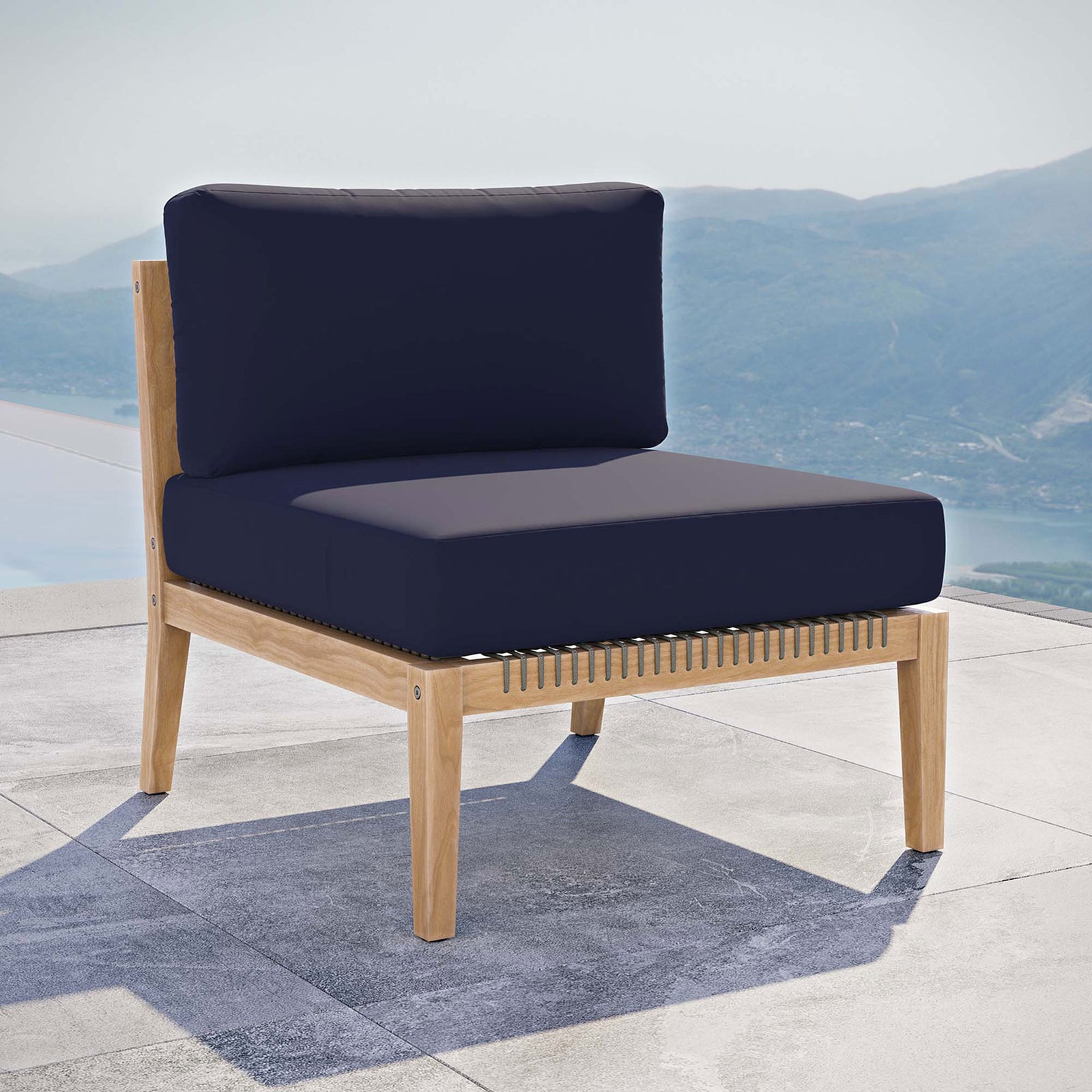 Navy teak armless chair positioned on a terrace, perfect for coastal inspired outdoor lounging || EEI-5856-GRY-NAV || front_angle_room