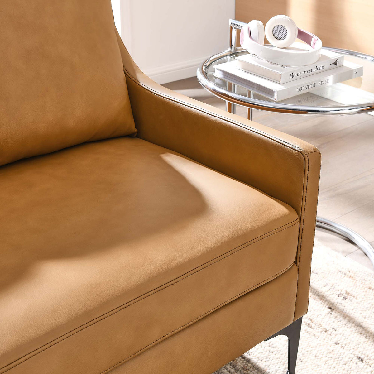 Lifestyle close up of tan leather loveseat arm with plush cushion beside a modern side table || EEI-6020-TAN || detail_room