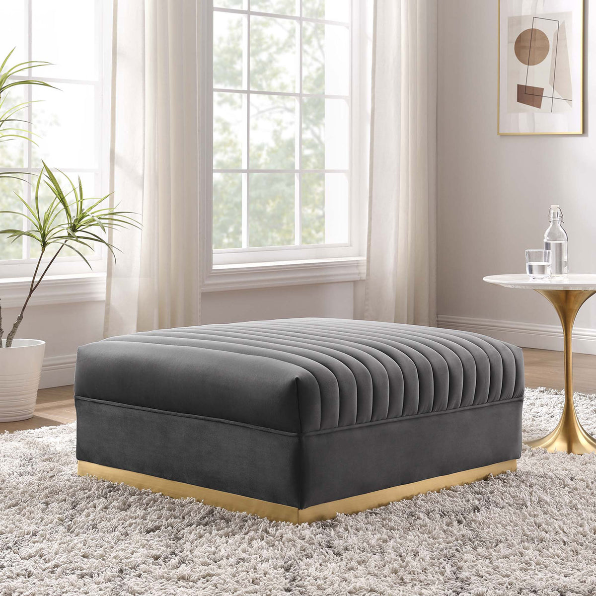 Gray velvet channel tufted ottoman styled in a bright modern living room with warm brass and marble accents. || EEI-6036-GRY || front_angle_room