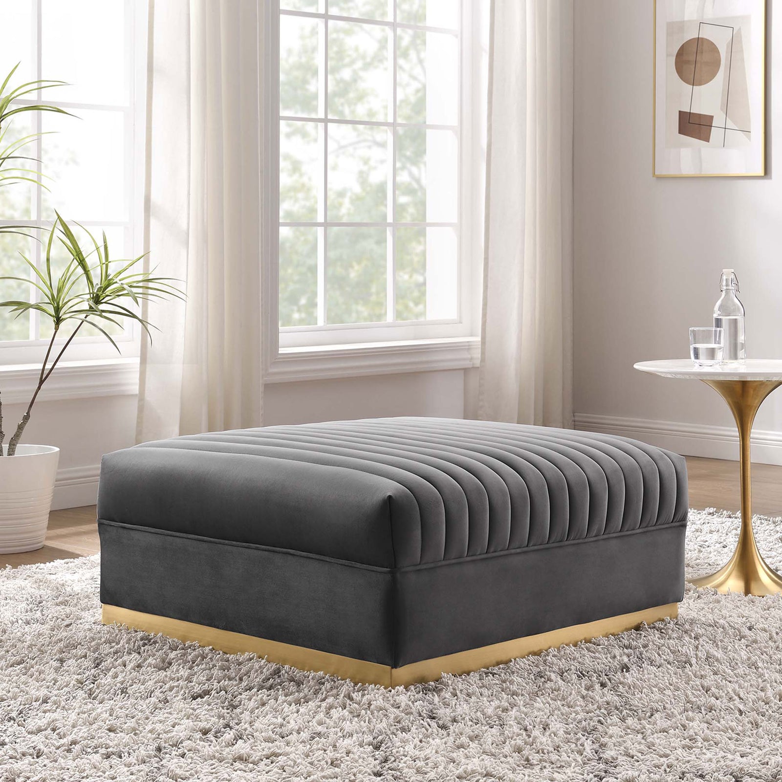 Gray velvet channel tufted ottoman styled in a bright modern living room with warm brass and marble accents. || EEI-6036-GRY || front_angle_room
