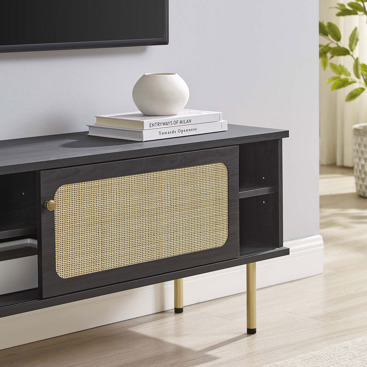 Black rattan TV stand styled under a wall-mounted TV with books and decor in a bright living room. || EEI-6044-BLK || storage_room