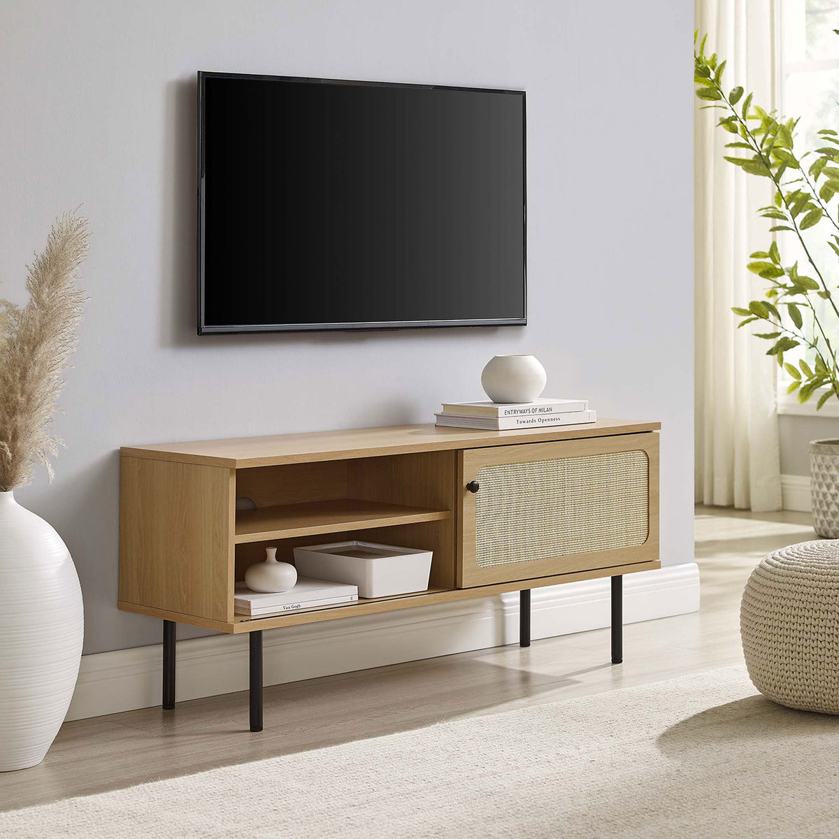 Oak TV console with rattan sliding door and black legs grounding a light, airy living space. || EEI-6044-OAK || front_angle_room