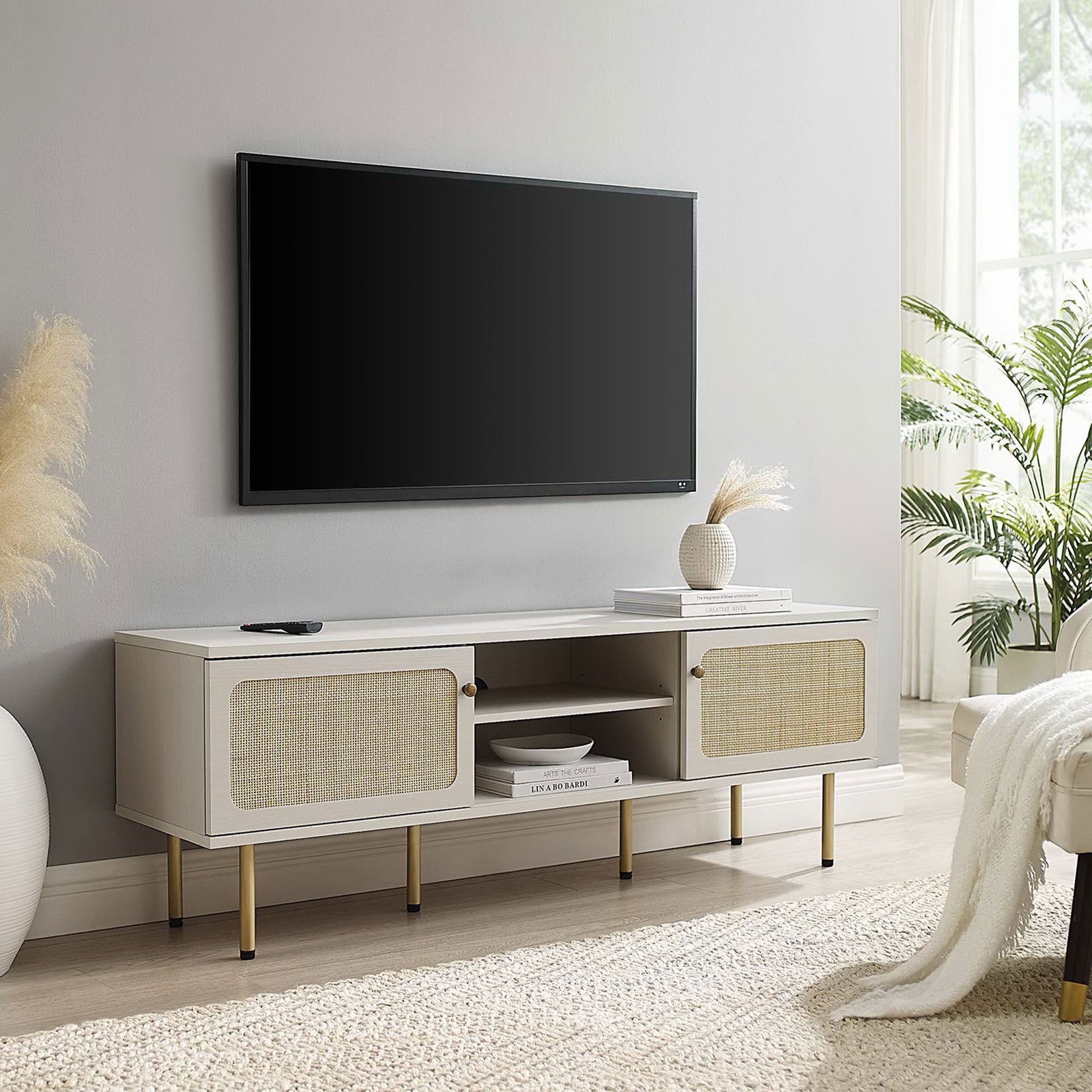 Long white TV console with dual rattan doors and gold legs anchoring an airy, neutral living space. || EEI-6045-WHI || front_angle_room
