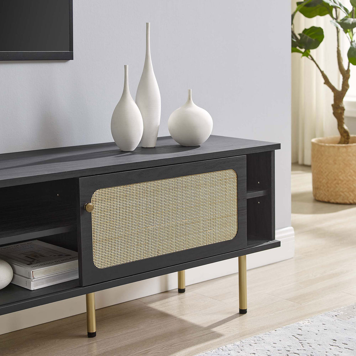 Black rattan TV stand stretching beneath a wall-mounted TV with vases and decor in a neutral room. || EEI-6046-BLK || storage_room