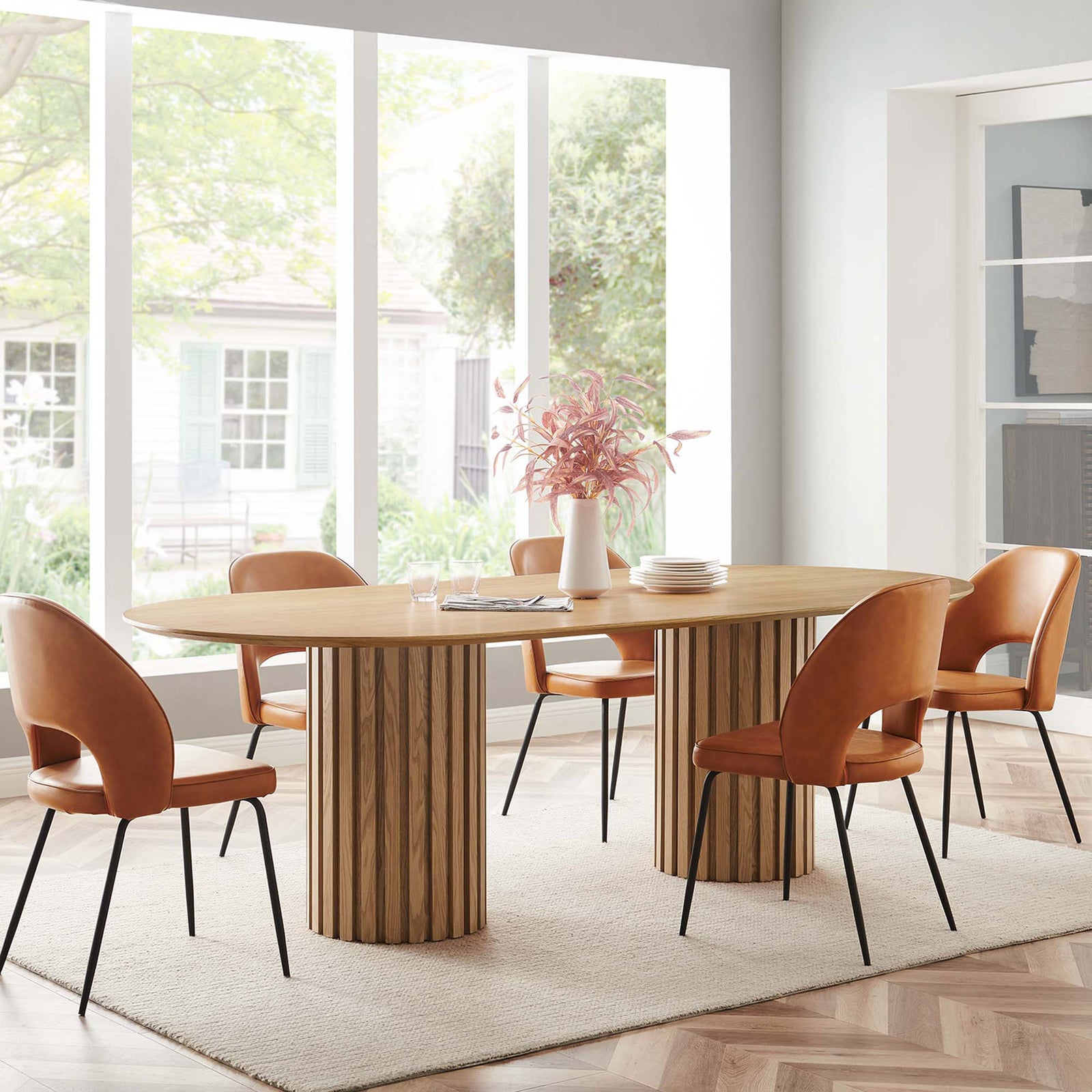 Senja oval oak dining table anchoring a bright dining room, paired with camel chairs on a textured rug || EEI-6065-OAK-SET || front_angle_room