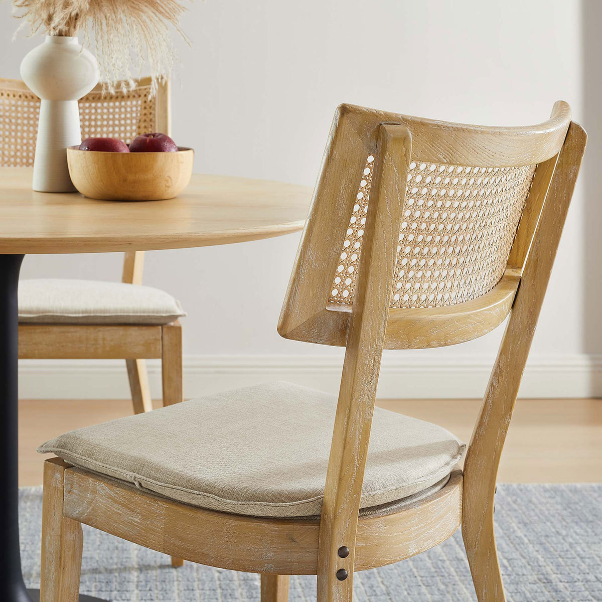 Detail view of curved cane backrest and cushioned seat at a round dining table || EEI-6080-GRY-BEI || detail_room
