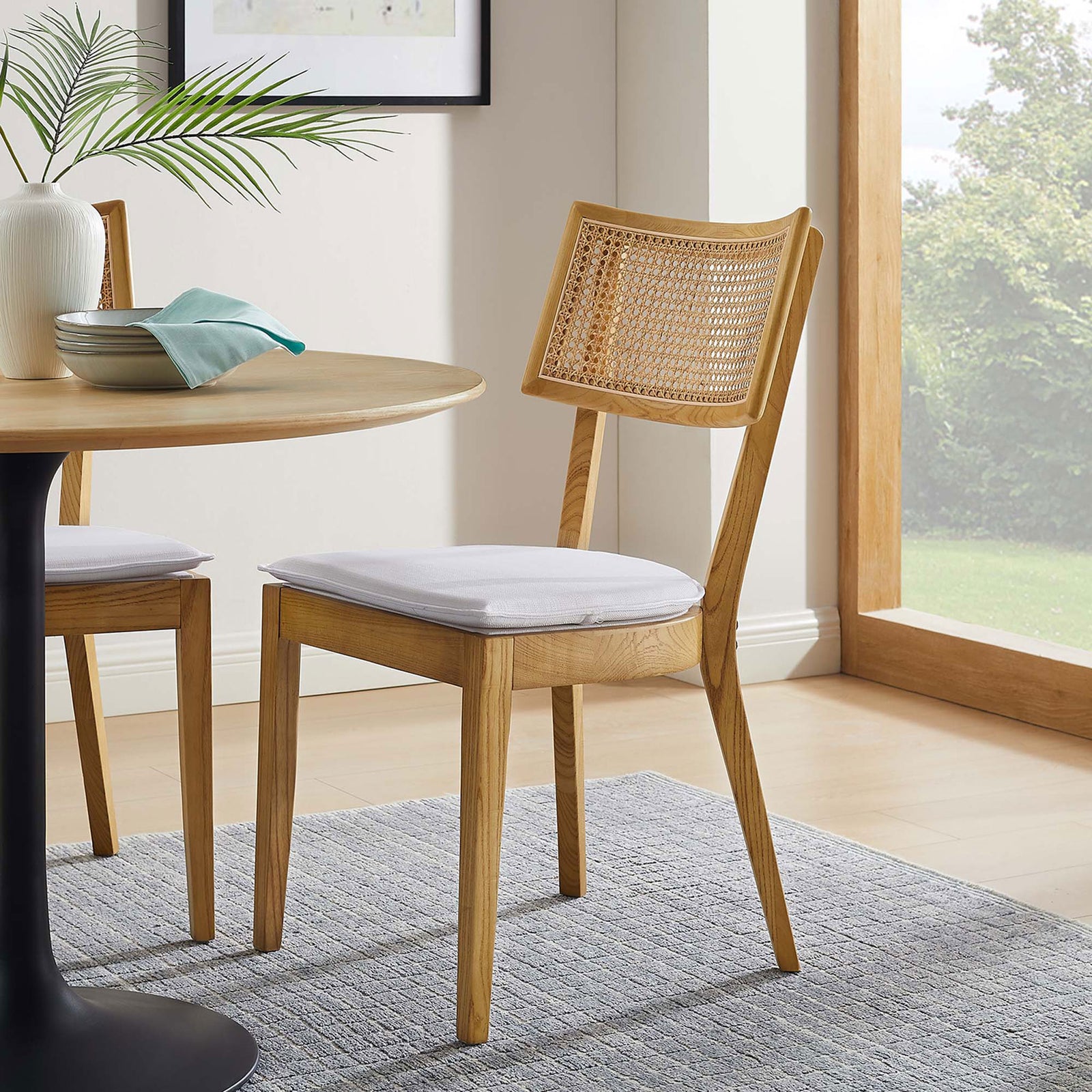 Caledonia dining chair styled at a round wood table, adding warm natural texture to a modern dining nook || EEI-6080-NAT-WHI || front_angle_room
