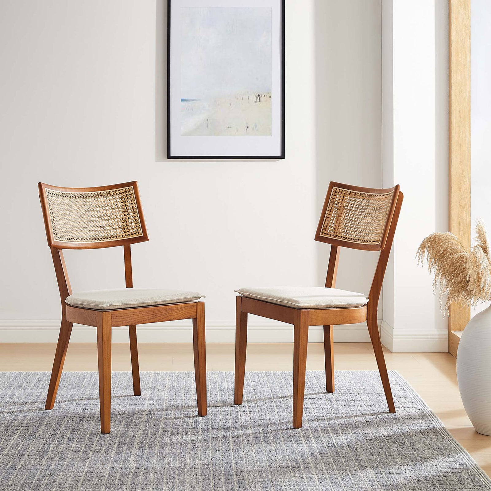 Pair of walnut and beige rattan back dining chairs arranged on a textured rug in a cozy dining room. || EEI-6080-WAL-BEI || front_angle_multi_room