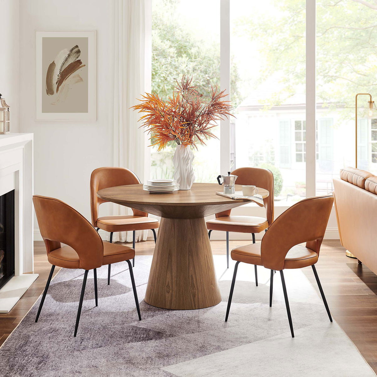 Walnut round dining table anchored in a bright modern dining room with coordinating upholstered chairs || EEI-6102-WAL || front_angle_room
