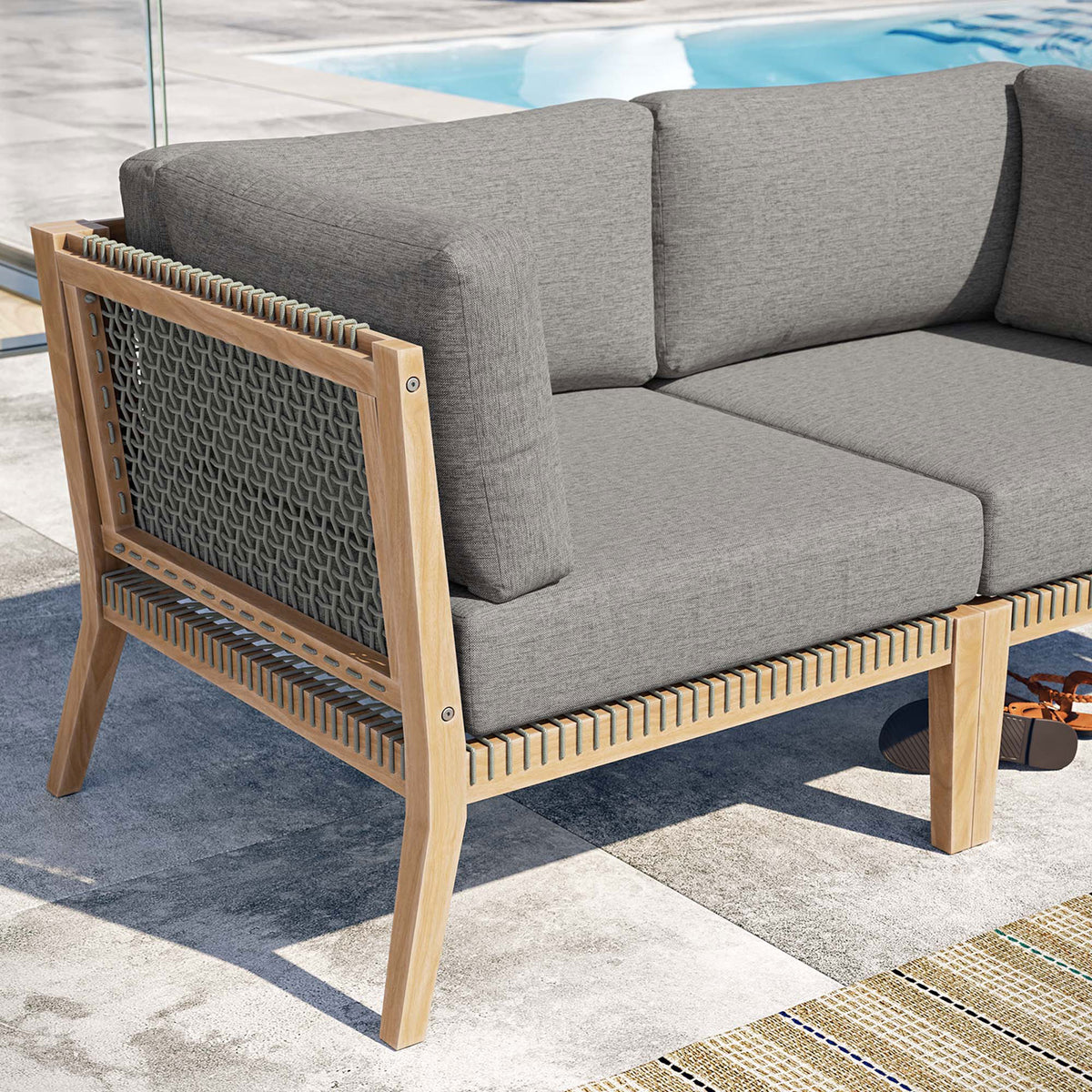 Poolside detail of teak frame, woven rope, and gray graphite cushions on the Clearwater loveseat || EEI-6119-GRY-GPH || detail_room