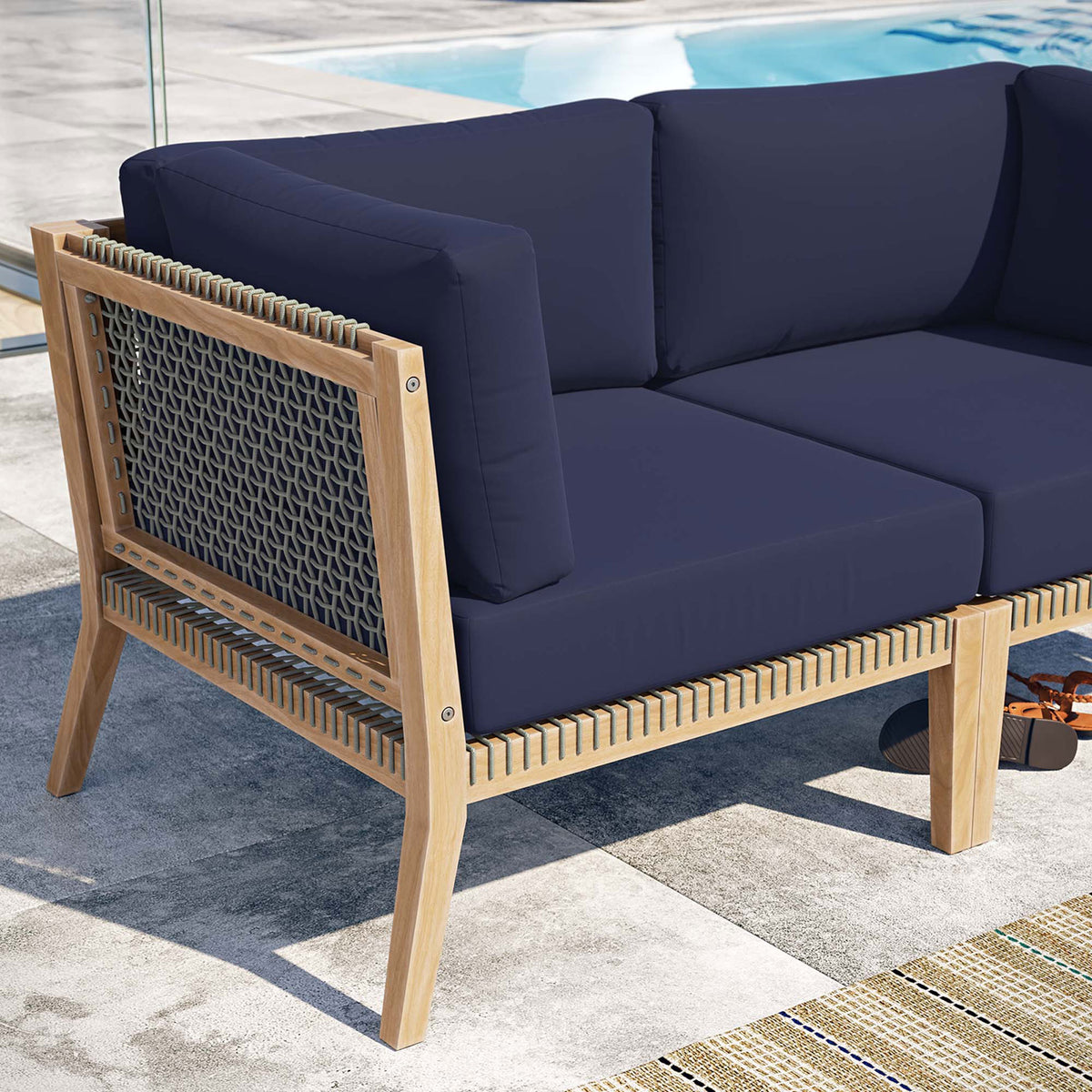 Poolside detail of teak frame, woven rope, and navy cushions on the Clearwater loveseat || EEI-6119-GRY-NAV || detail_room