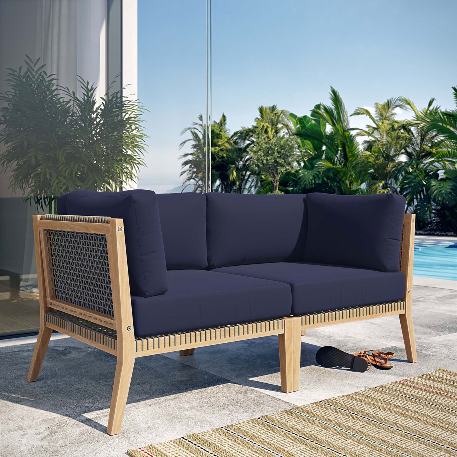Clearwater teak loveseat with navy cushions styled on a sunlit poolside patio || EEI-6119-GRY-NAV || front_angle_room