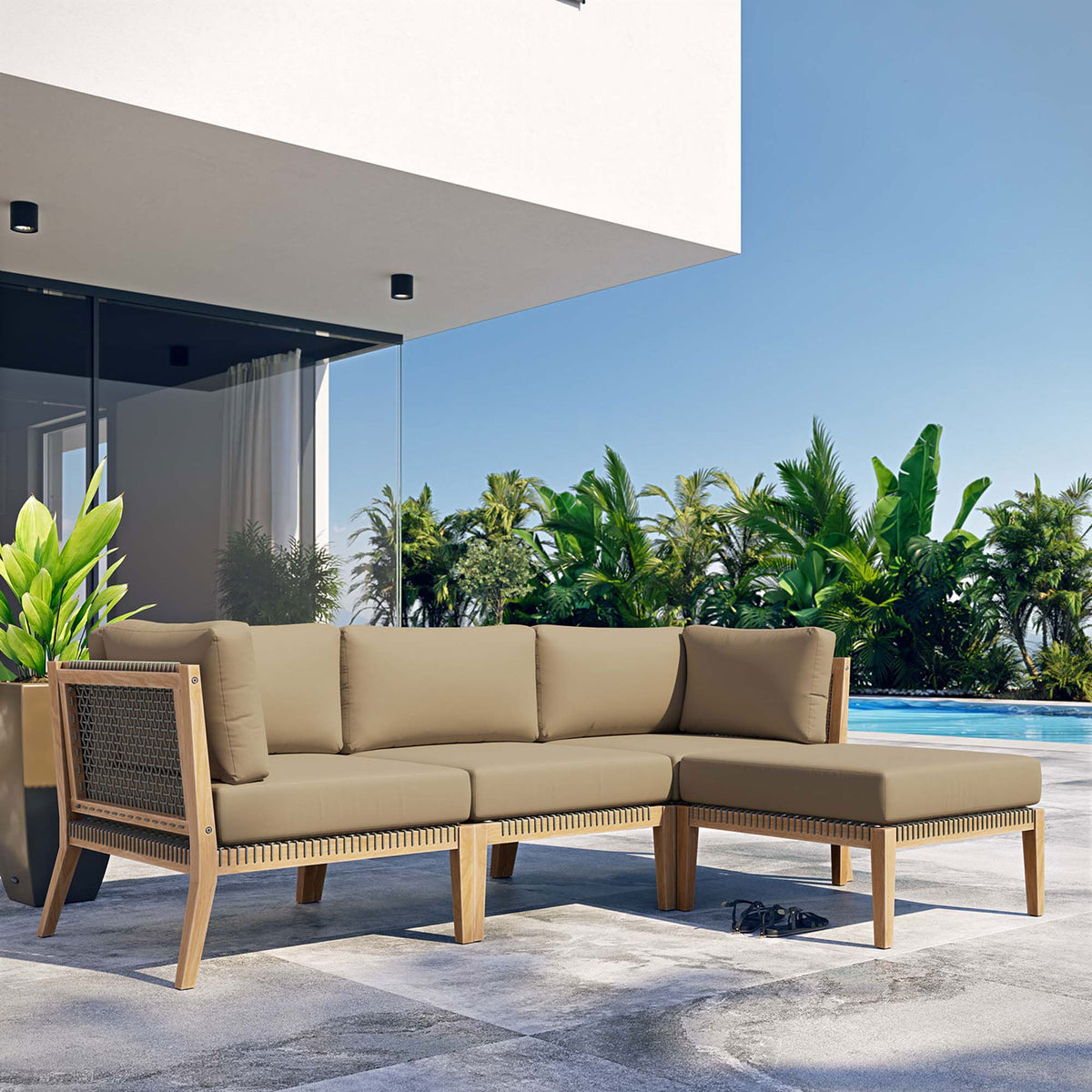 Light brown teak sectional sofa by the pool framed by palm trees and modern architecture || EEI-6121-GRY-LBR || front_angle_room