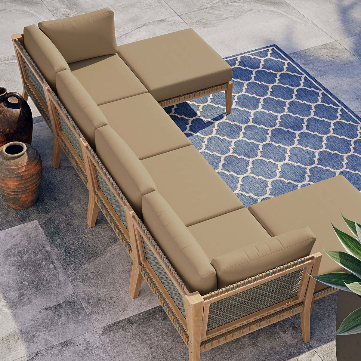Light brown teak sectional styled on a modern patio with blue patterned rug and planters || EEI-6122-GRY-LBR || top_angle_room