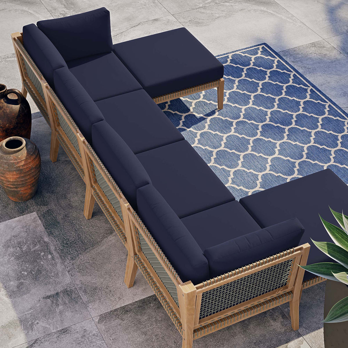 Navy blue teak sectional styled on a modern patio with blue patterned rug and planters || EEI-6122-GRY-NAV || top_angle_room