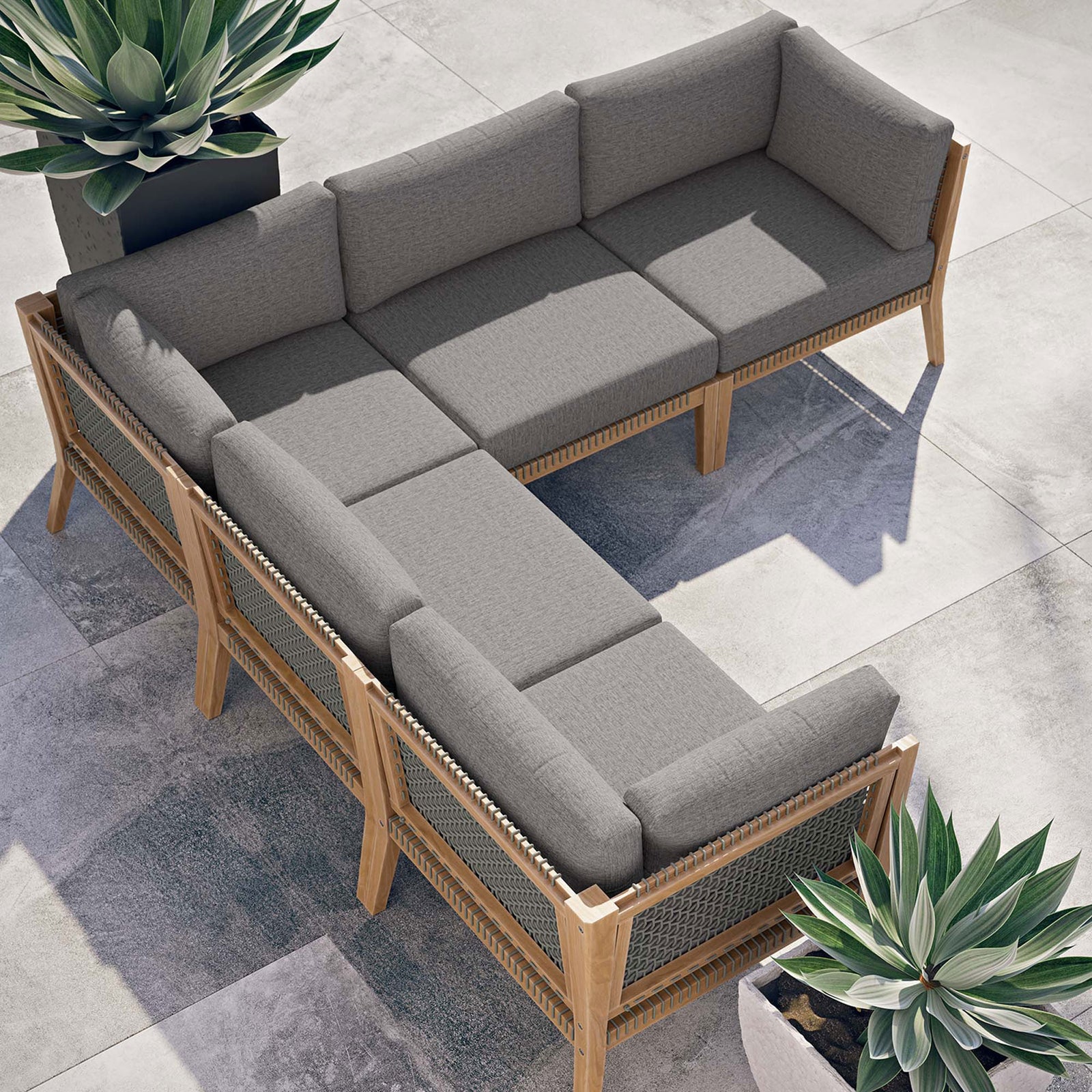 Outdoor patio scene with gray graphite sectional arranged in an L shape between lush potted succulents || EEI-6123-GRY-GPH || top_angle_room