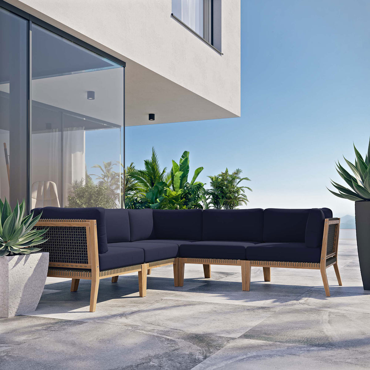 Contemporary terrace featuring a navy teak sectional set beside glass walls and lush greenery || EEI-6123-GRY-NAV || front_angle_room