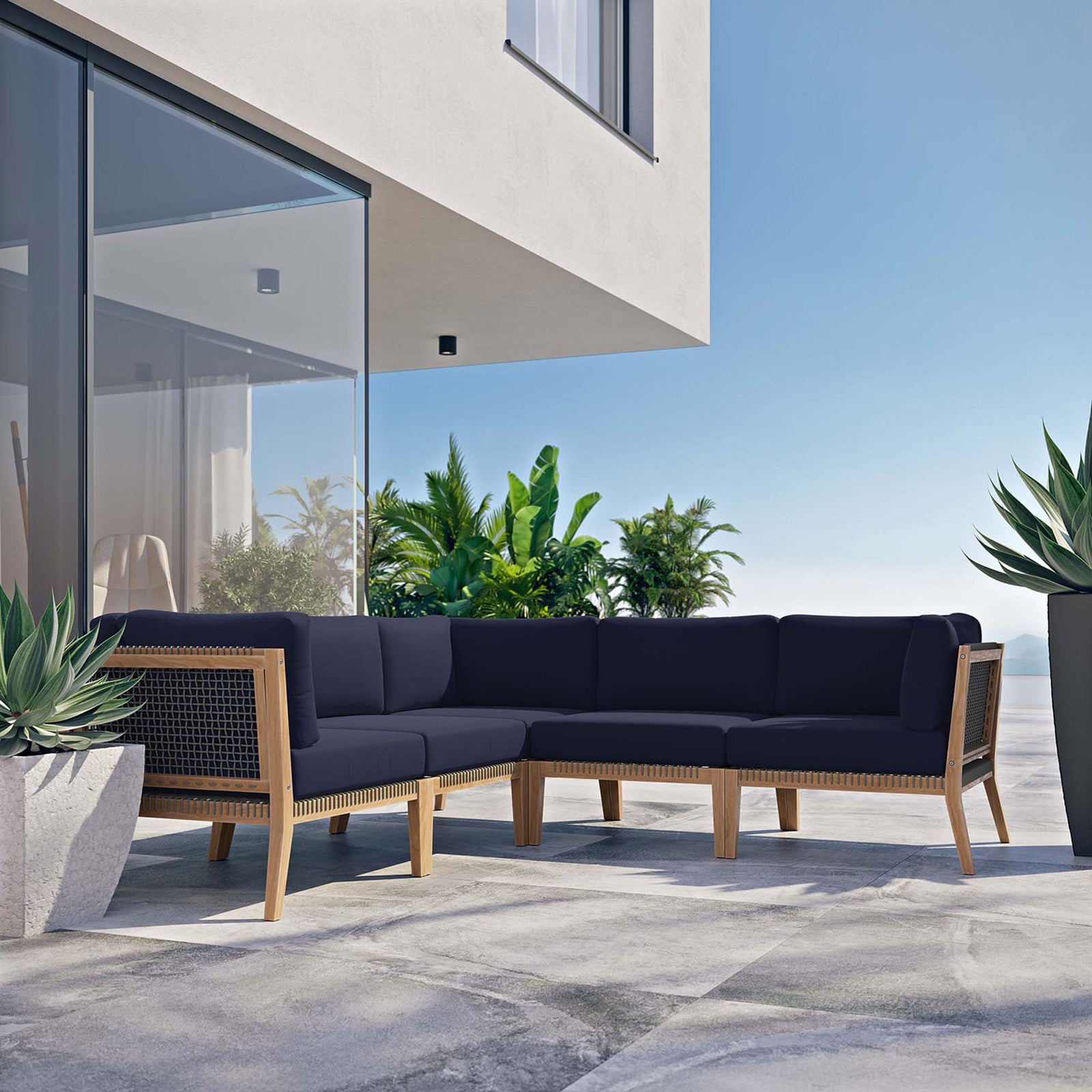 Contemporary terrace featuring a navy teak sectional set beside glass walls and lush greenery || EEI-6123-GRY-NAV || front_angle_room