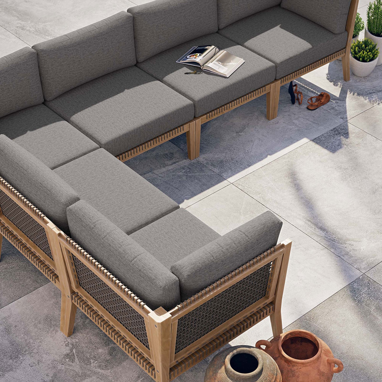 Gray graphite sectional arranged on a modern patio with open book and decor accessories || EEI-6125-GRY-GPH || top_angle_room