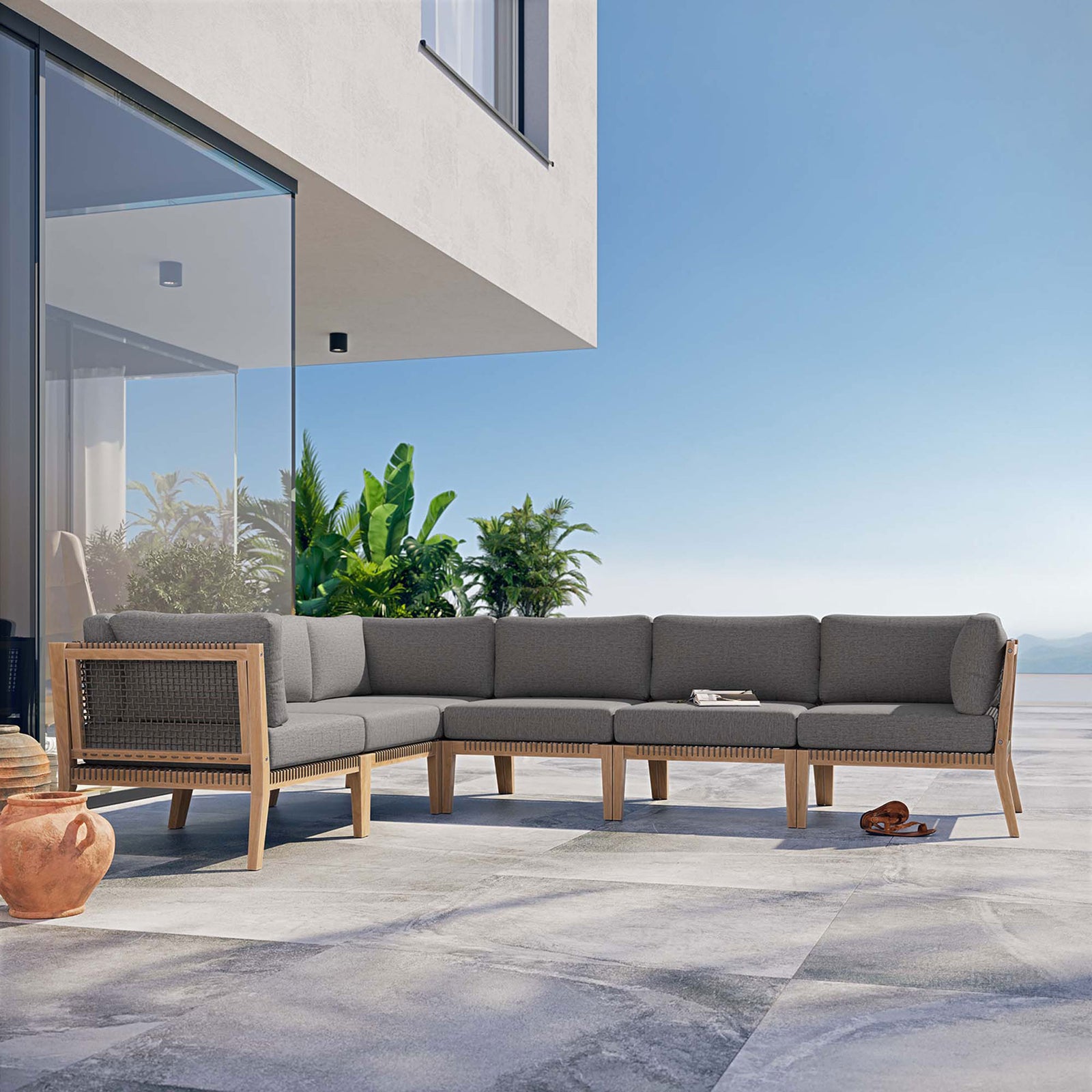 Gray graphite sectional styled on a sunny terrace with ocean and greenery backdrop || EEI-6125-GRY-GPH || front_angle_room