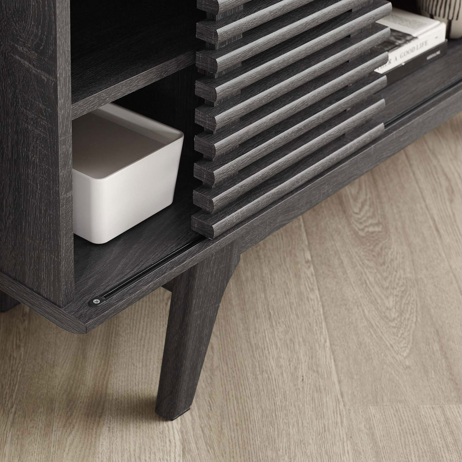 Charcoal TV stand shelf, slatted door edge, and tapered leg styled with books and a storage bin || EEI-6157-CHA || detail_room