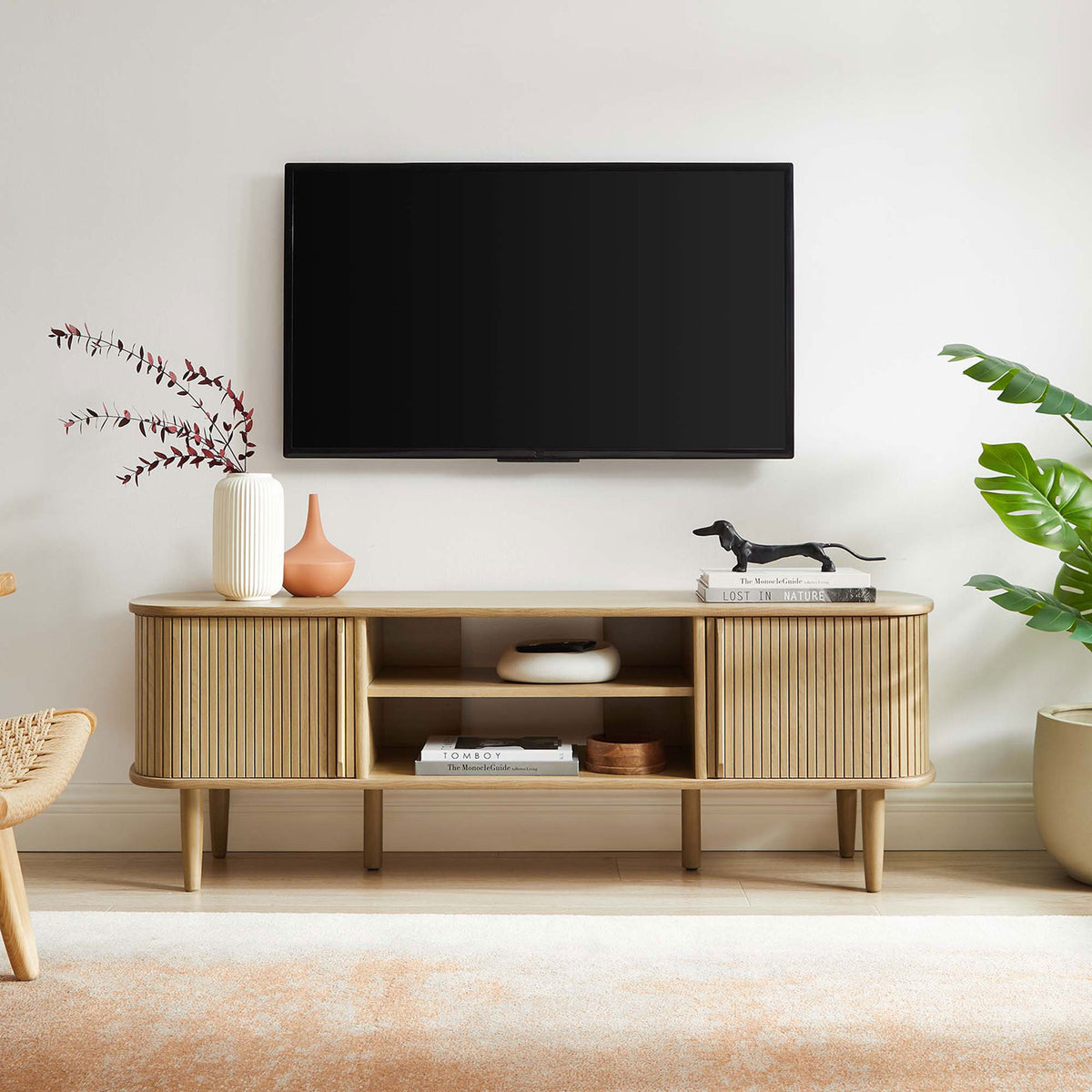 Oak Contour TV stand styled in a modern living room beneath a wall-mounted TV || EEI-6158-OAK || front_room