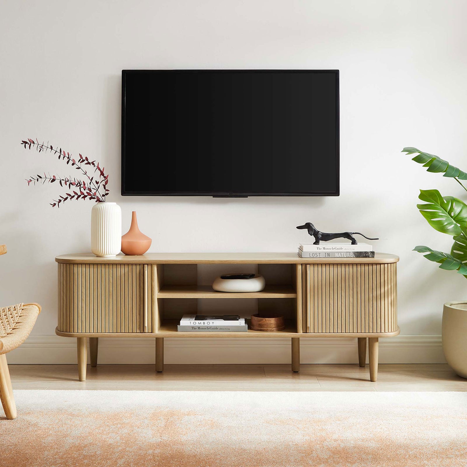 Oak Contour TV stand styled in a modern living room beneath a wall-mounted TV || EEI-6158-OAK || front_room