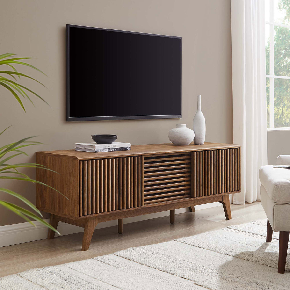 Walnut slatted-door TV stand anchors a bright living room beneath a wall-mounted TV with minimalist decor || EEI-6180-WAL || front_angle_room