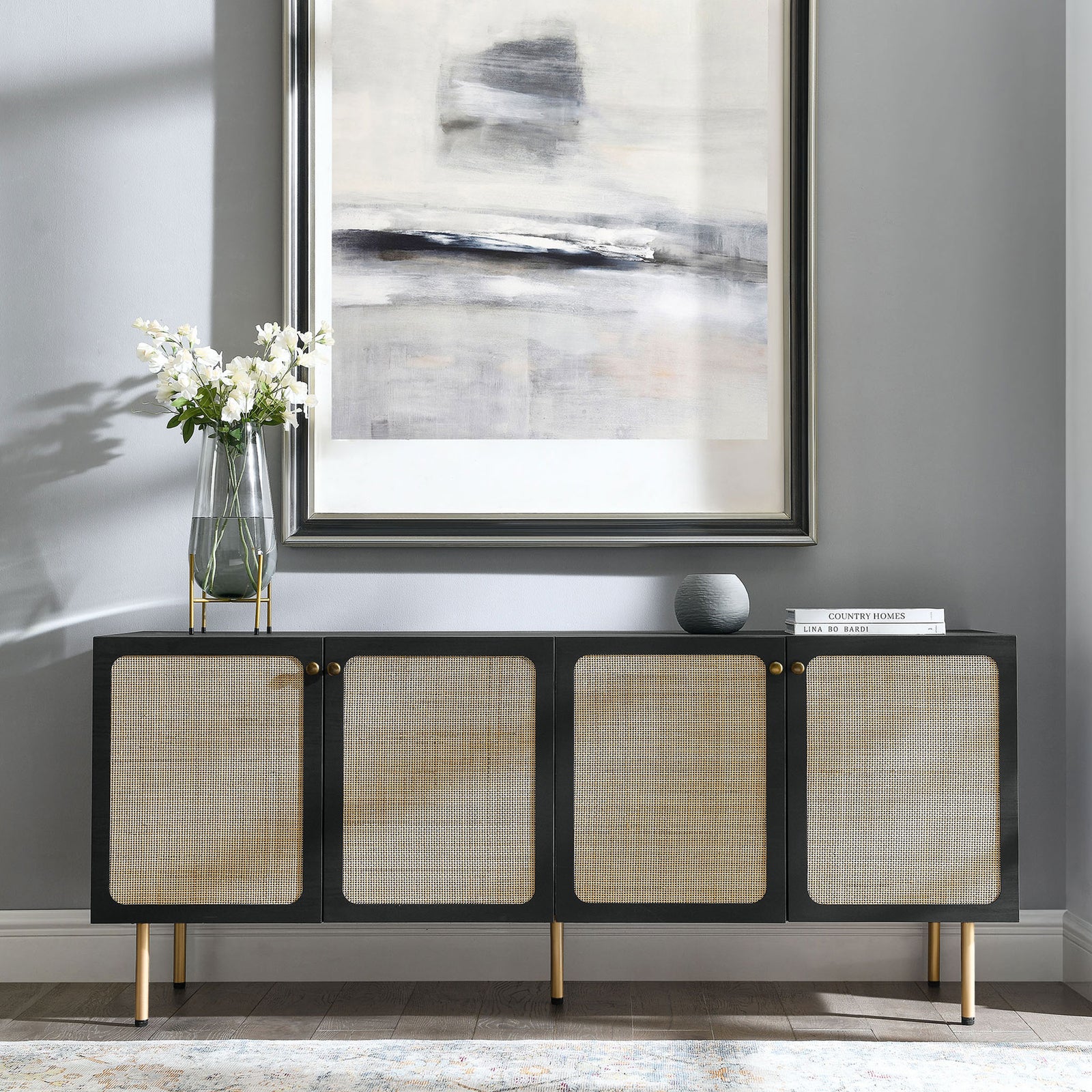Black rattan front sideboard styled beneath contemporary artwork in a bright modern living space || EEI-6201-BLK || front_angle_room