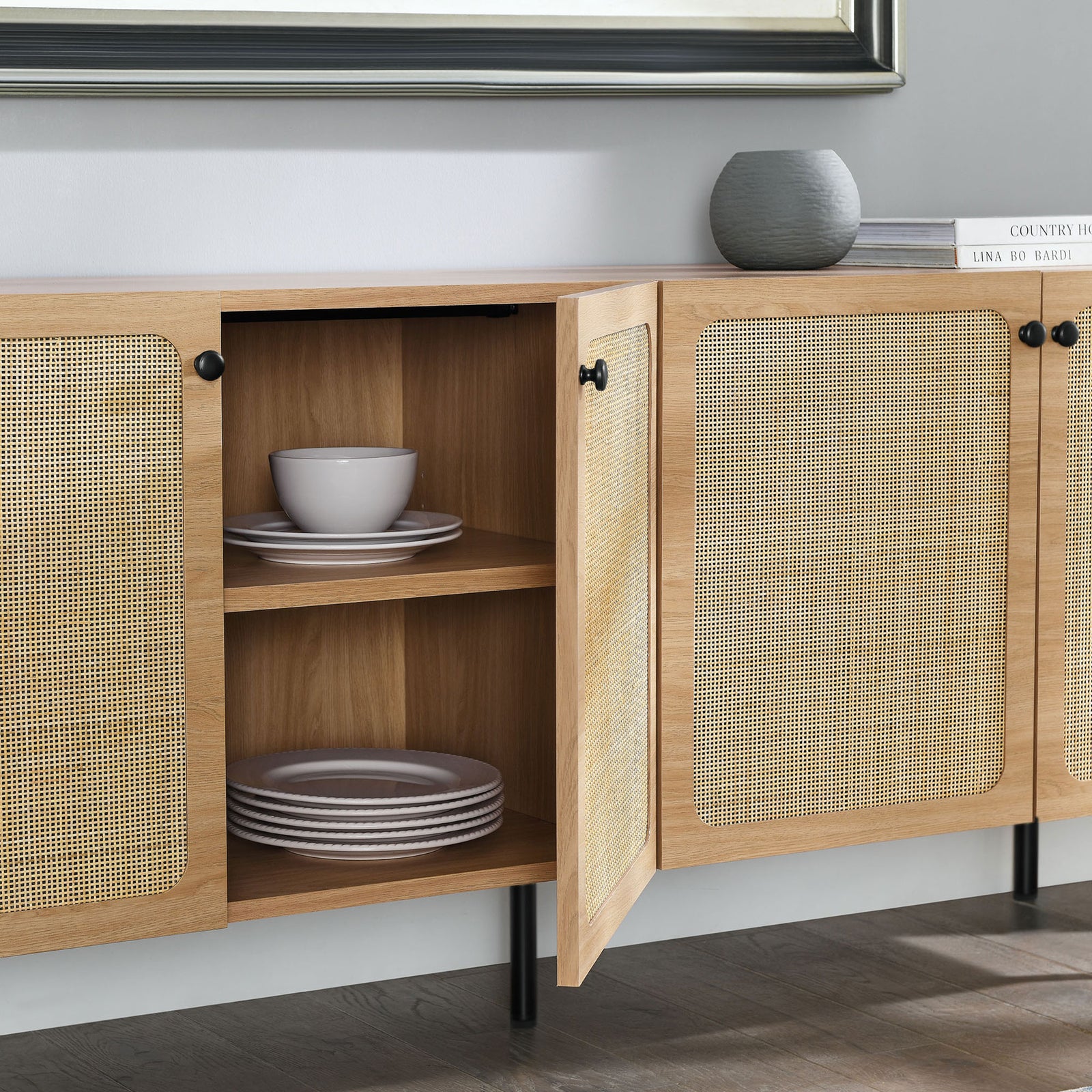 Open sideboard doors revealing shelves neatly organized with dinnerware in a bright living space || EEI-6201-OAK || storage_open_room