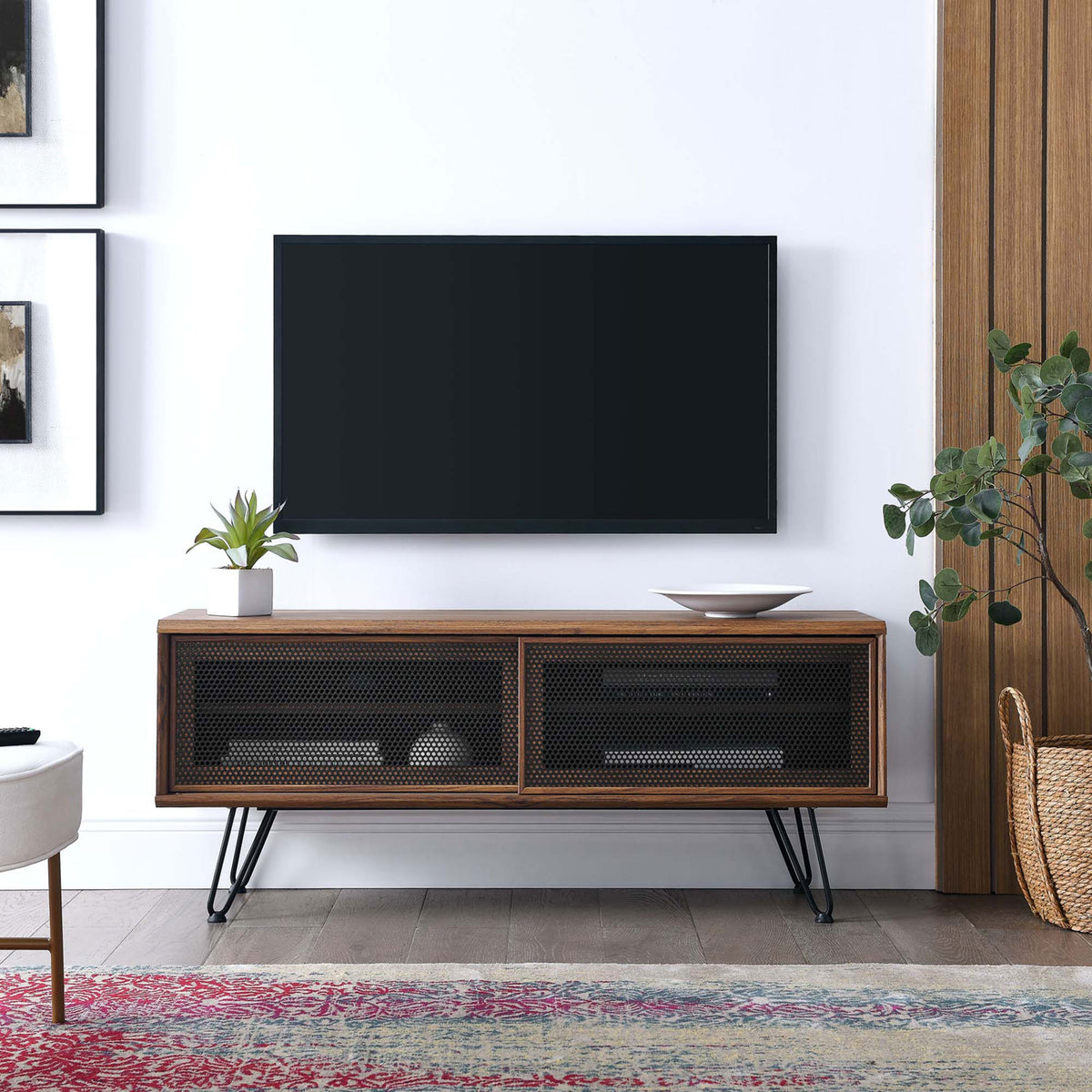 Walnut 47 inch TV stand with black mesh doors and hairpin legs anchoring a modern living room setup || EEI-6202-WAL || front_angle_room