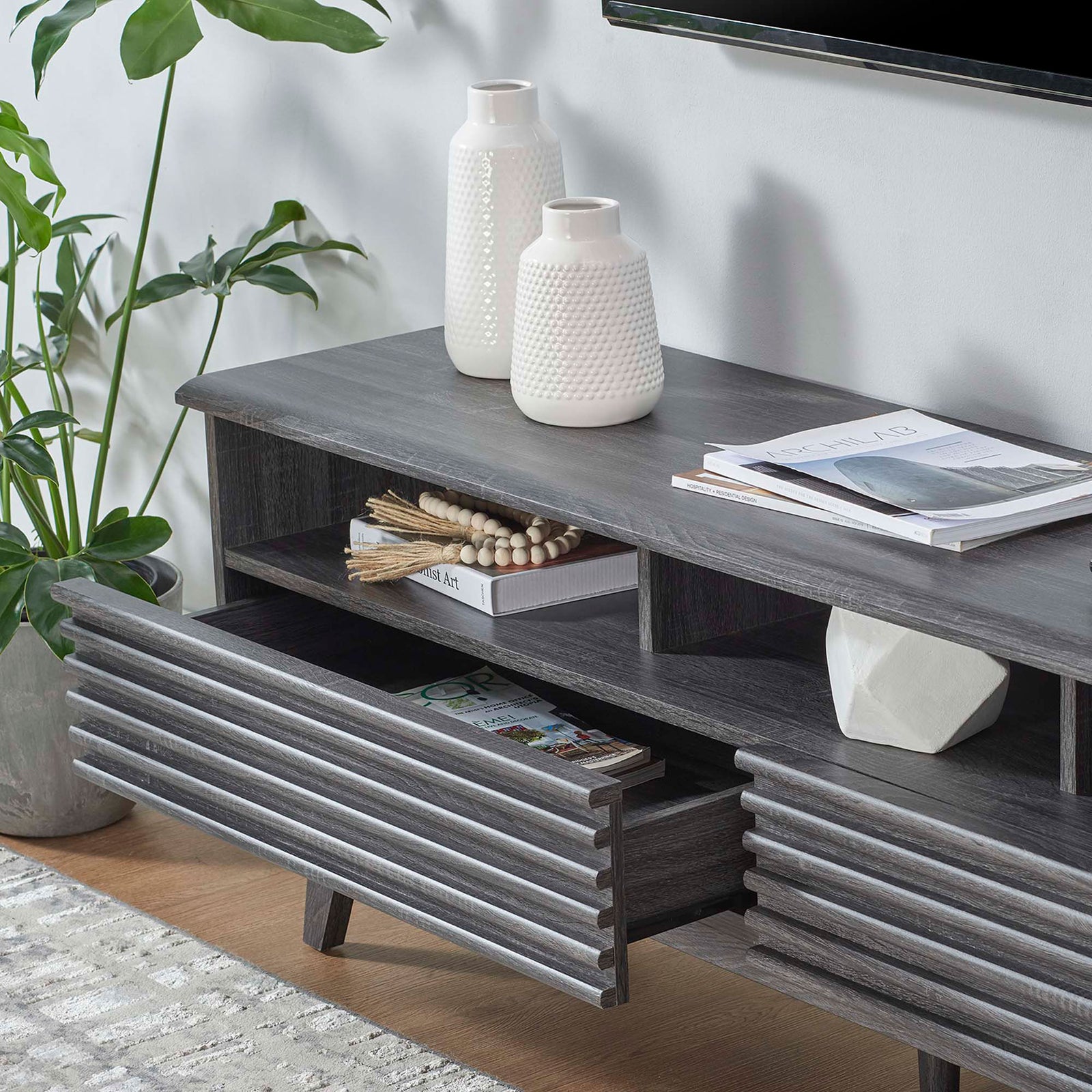Charcoal TV stand styled with decor accents and open drawer storing books and magazines || EEI-6228-CHA || storage_open_room