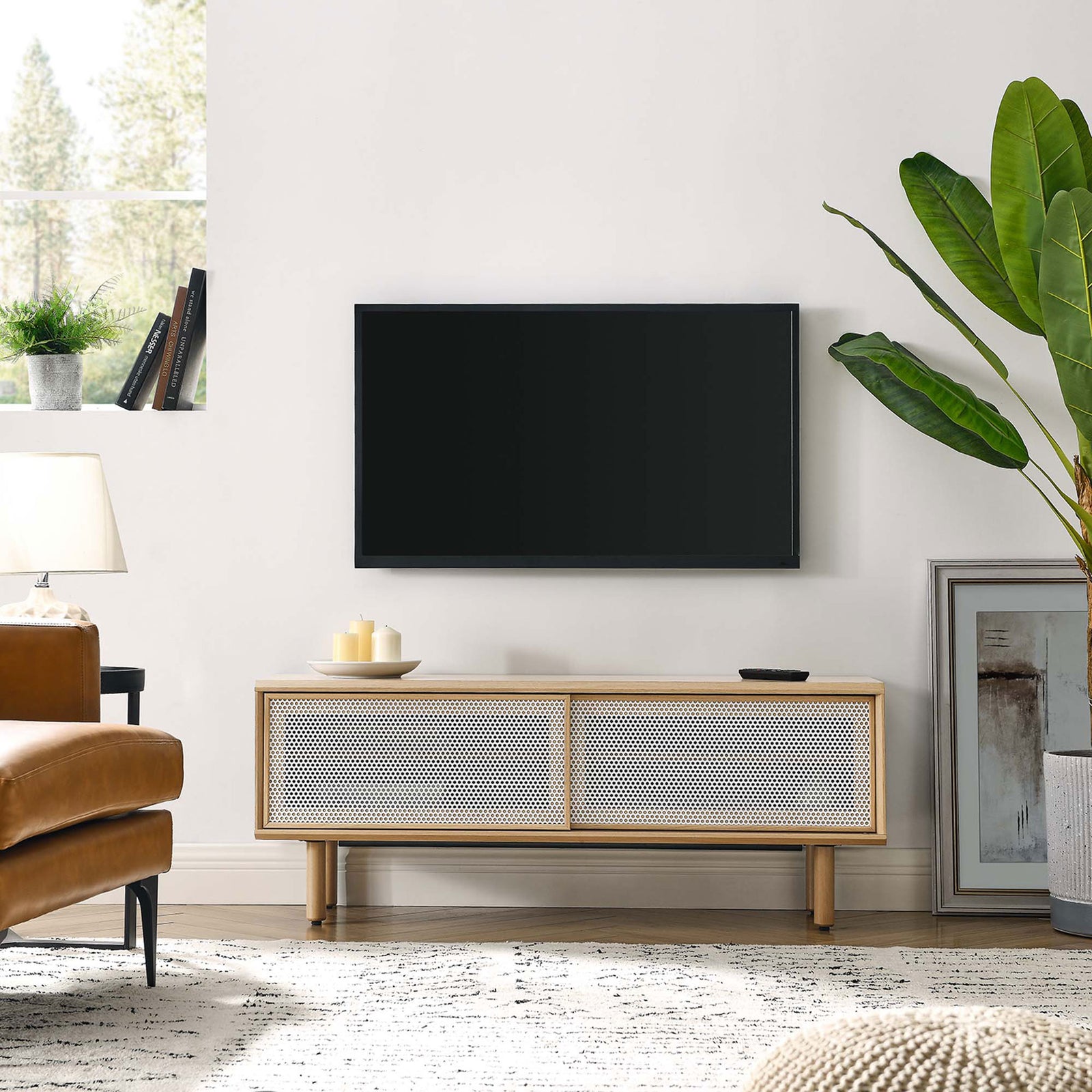 Kurtis 47 in oak TV stand in a bright living room beneath a wall-mounted television || EEI-6233-OAK || front_angle_room