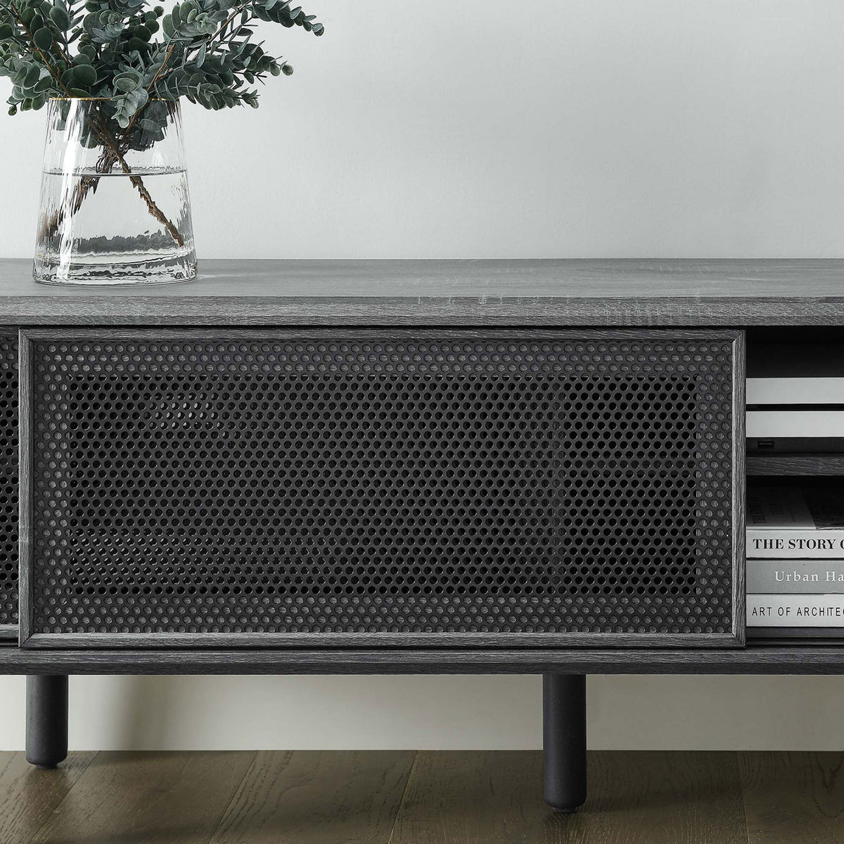 Styled charcoal TV stand topped with vase and books, highlighting textured mesh door and open shelf || EEI-6234-CHA || detail_room