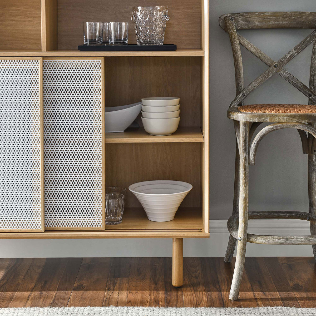 Open oak shelves neatly hold bowls and glassware, with white mesh doors adding texture to the vignette. || EEI-6237-OAK || detail_room